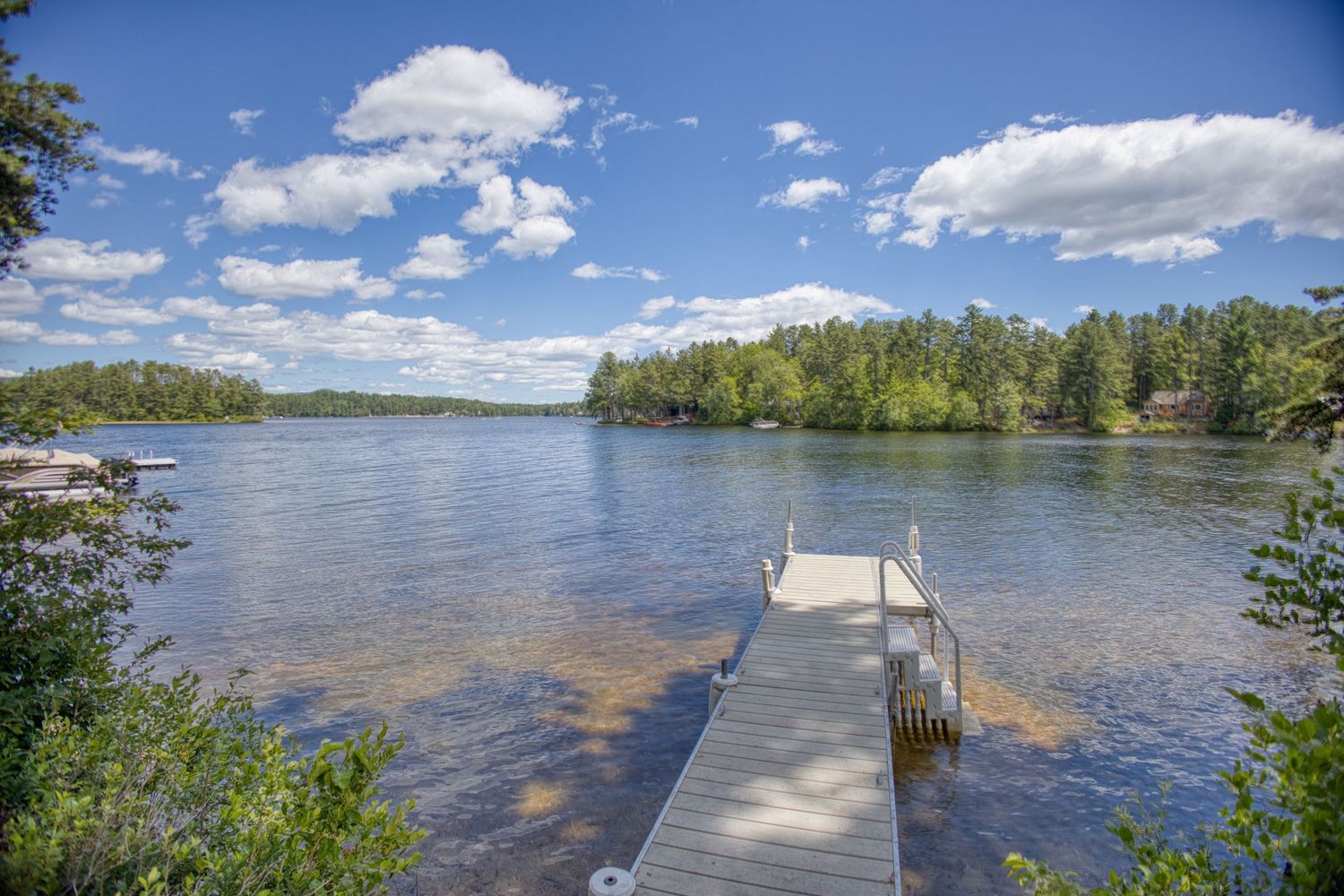 A panoramic series of lake views shows a wooden dock stretching into calm waters surrounded by lush green trees.