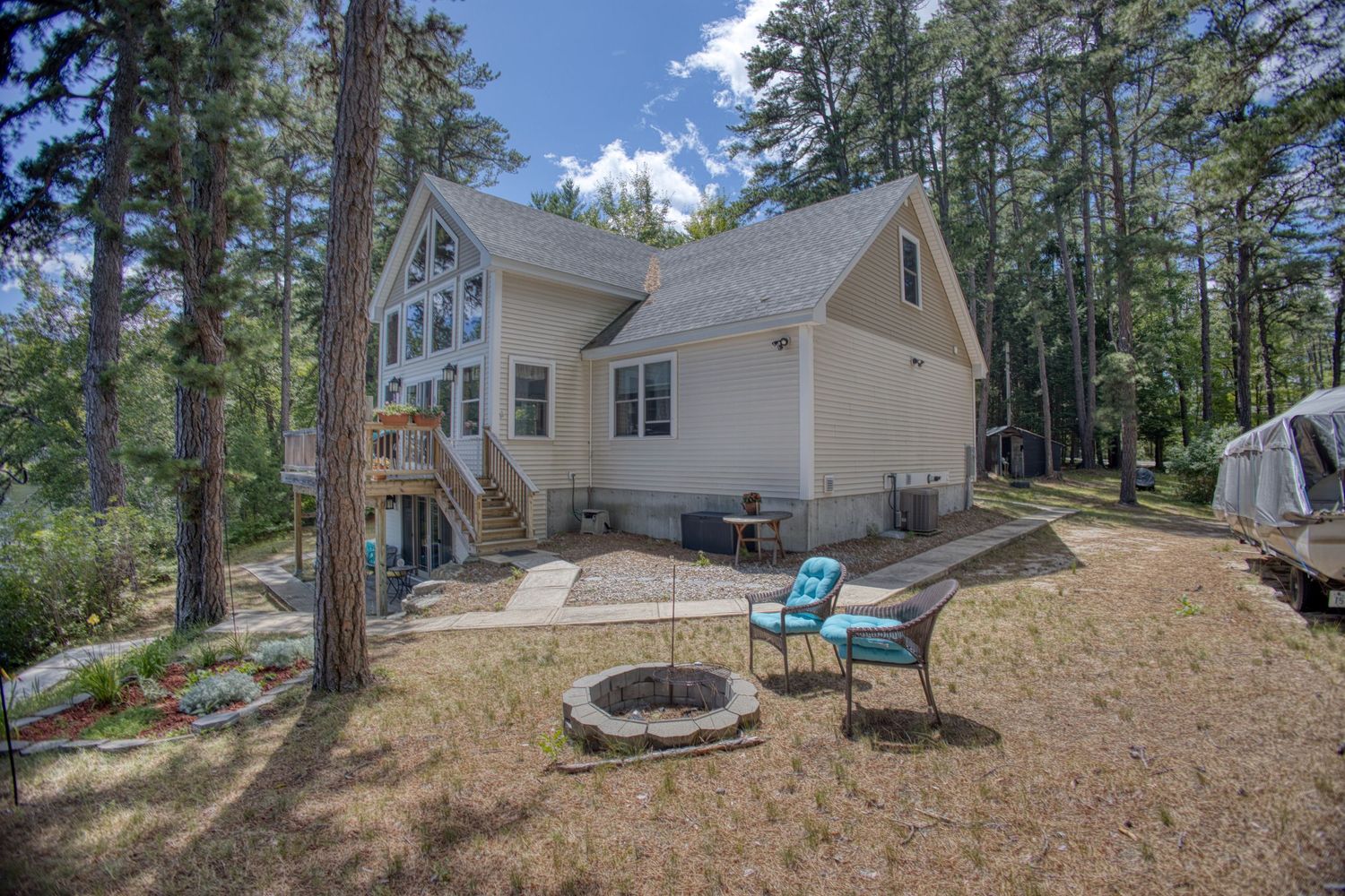 Panoramic view of a newly constructed home surrounded by tall pine trees on a sloped, natural terrain.