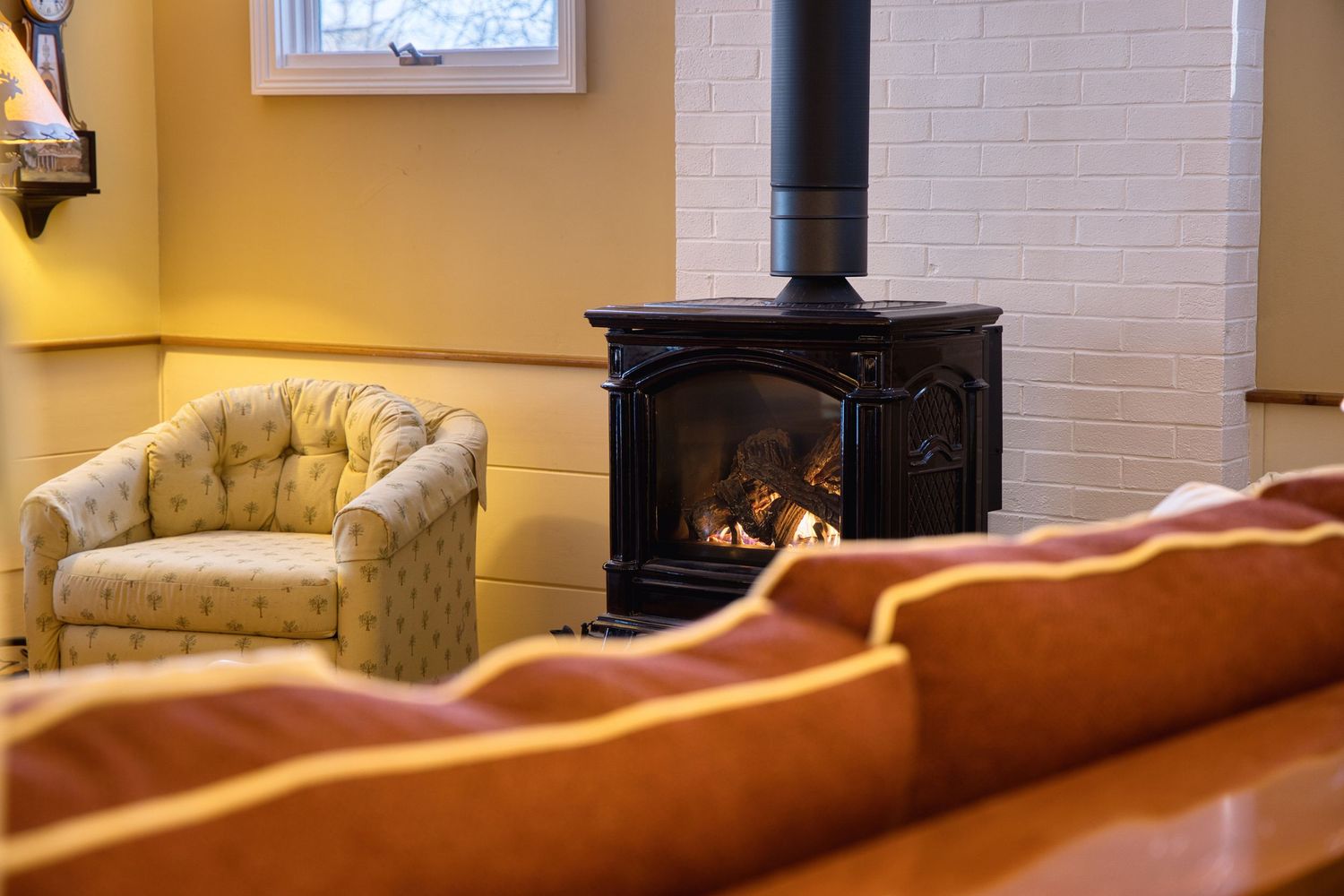 A cozy living room interior with exposed brick walls, a fireplace, and warm lighting creating an inviting atmosphere.