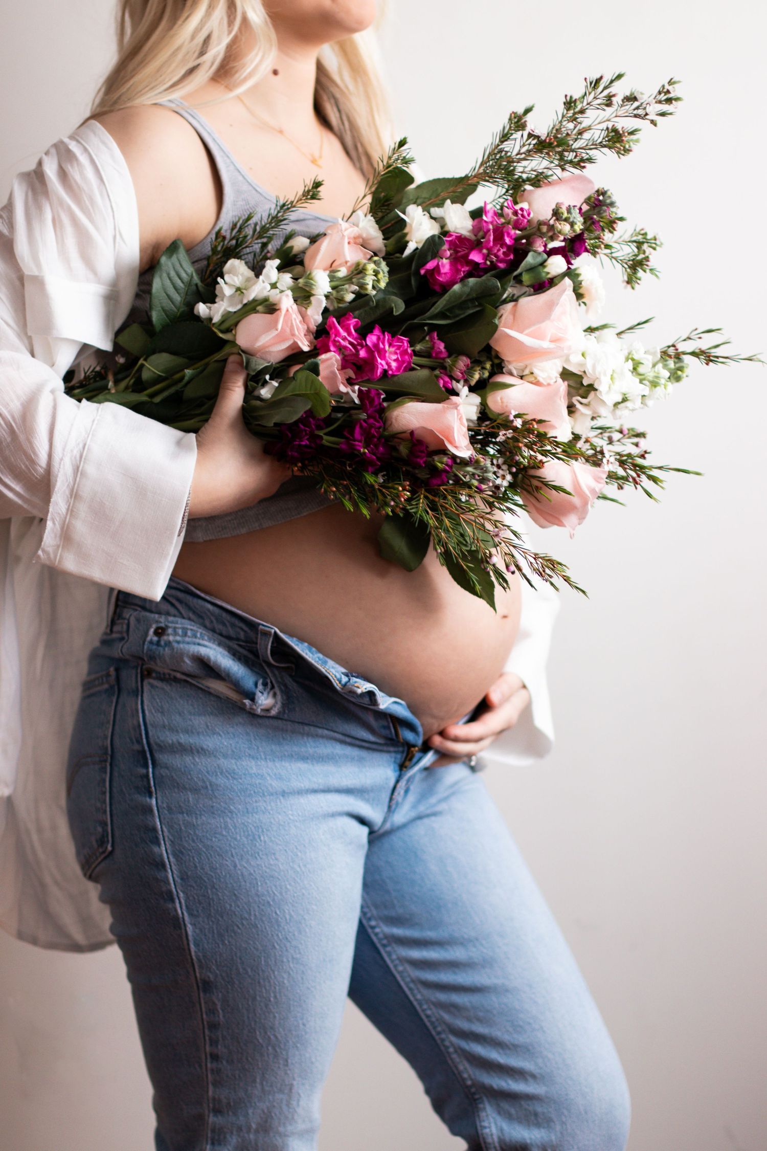Person holding vibrant pink and white floral bouquet against light background.