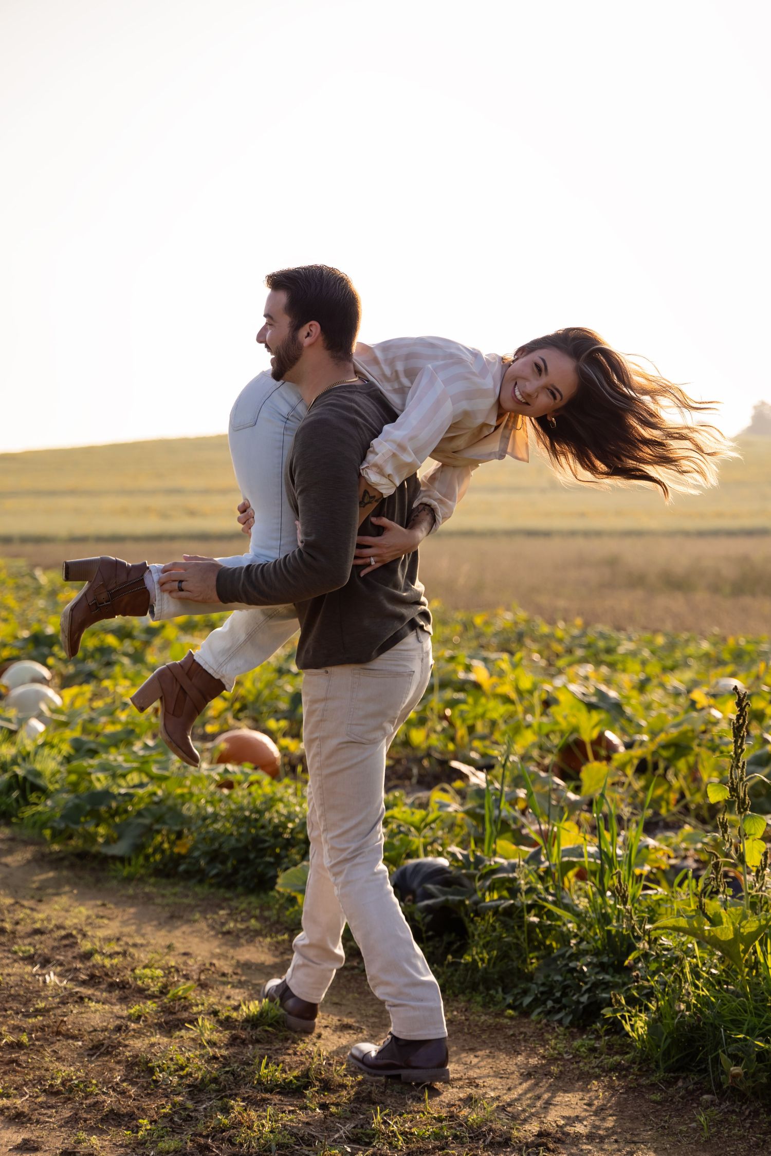 Couple embracing in a sunlit field of yellow flowers during golden hour, creating dynamic dancing poses.