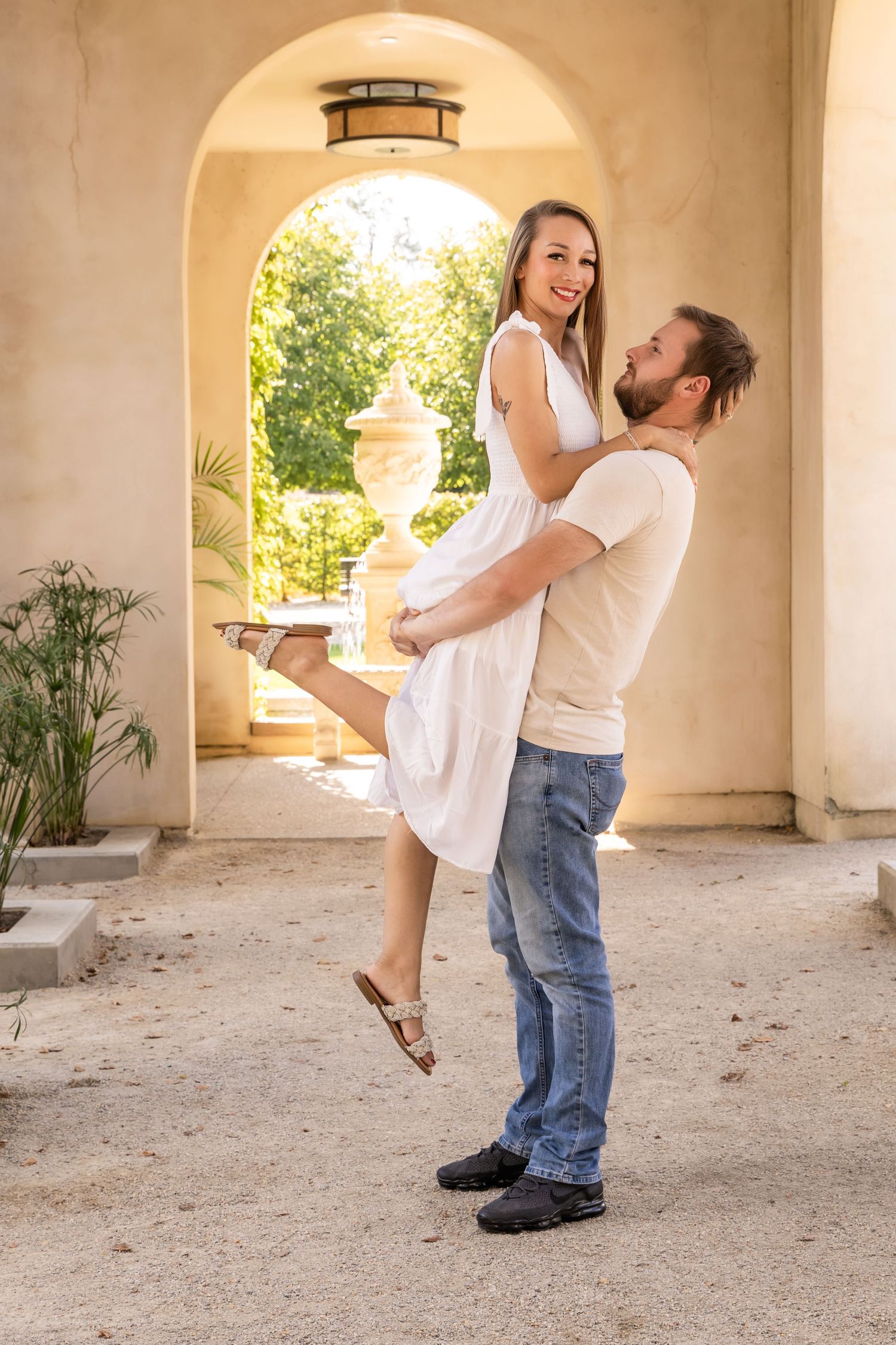 A romantic couple dances and embraces under arched columns in an outdoor courtyard setting.