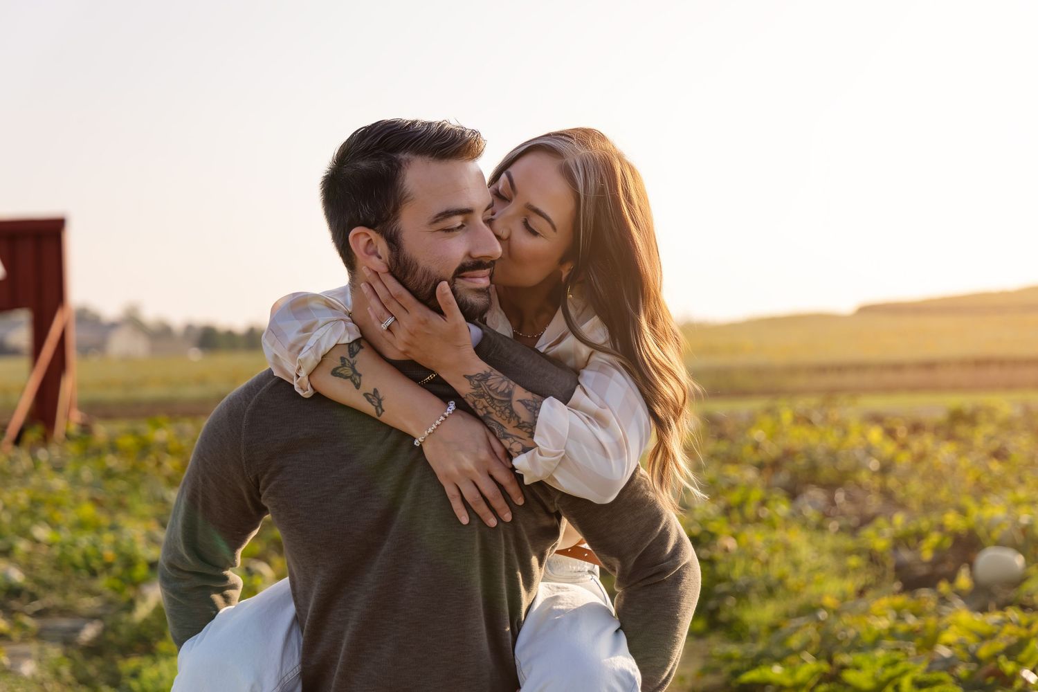 Happy couple sharing an intimate moment outdoors in a field during golden hour sunset.