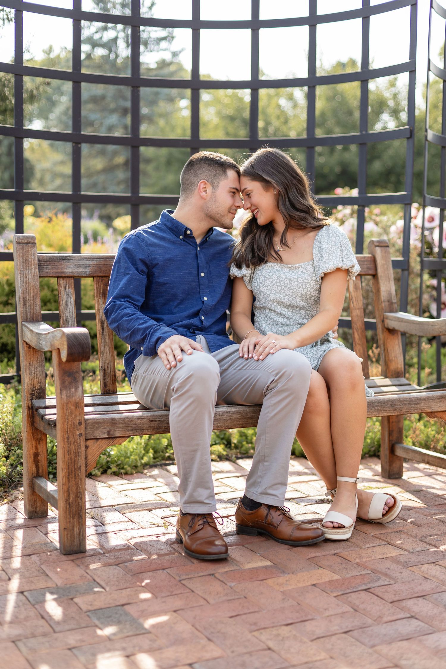 A romantic couple shares intimate moments sitting together on wooden benches in a sunlit glass-enclosed patio.