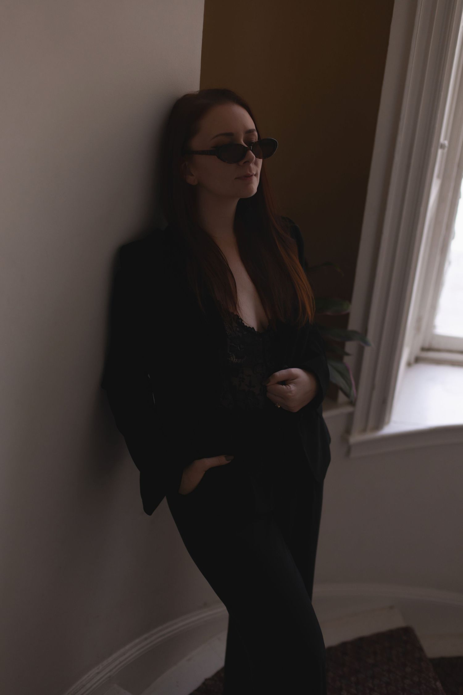 Silhouetted figure in black clothing creating dramatic poses near a window.