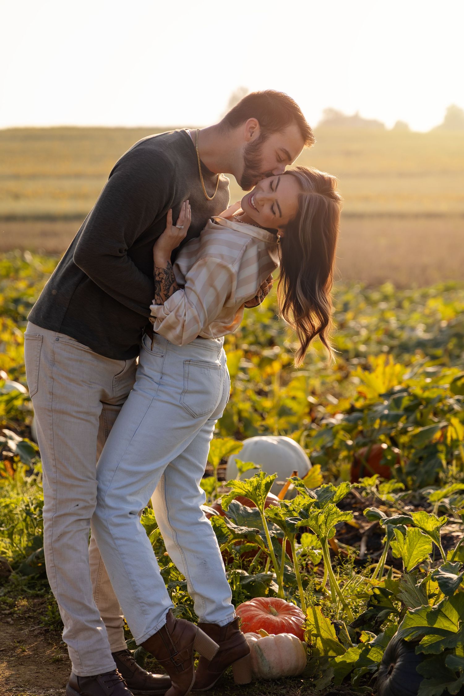 A romantic couple embraces in a sunlit field of yellow flowers during golden hour.