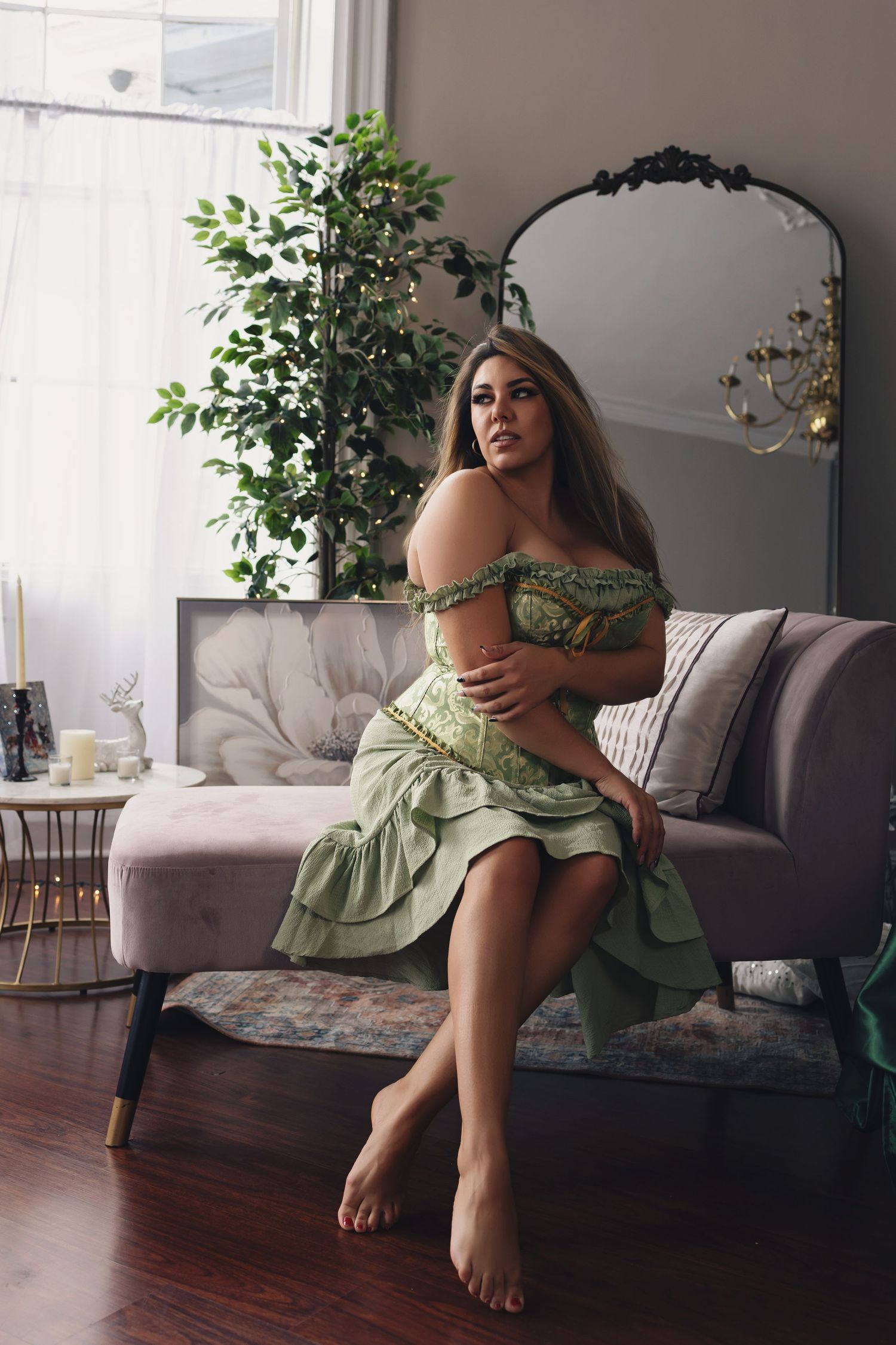 Intimate portrait session with mint green dress on grey couch in modern living room with hardwood floors.