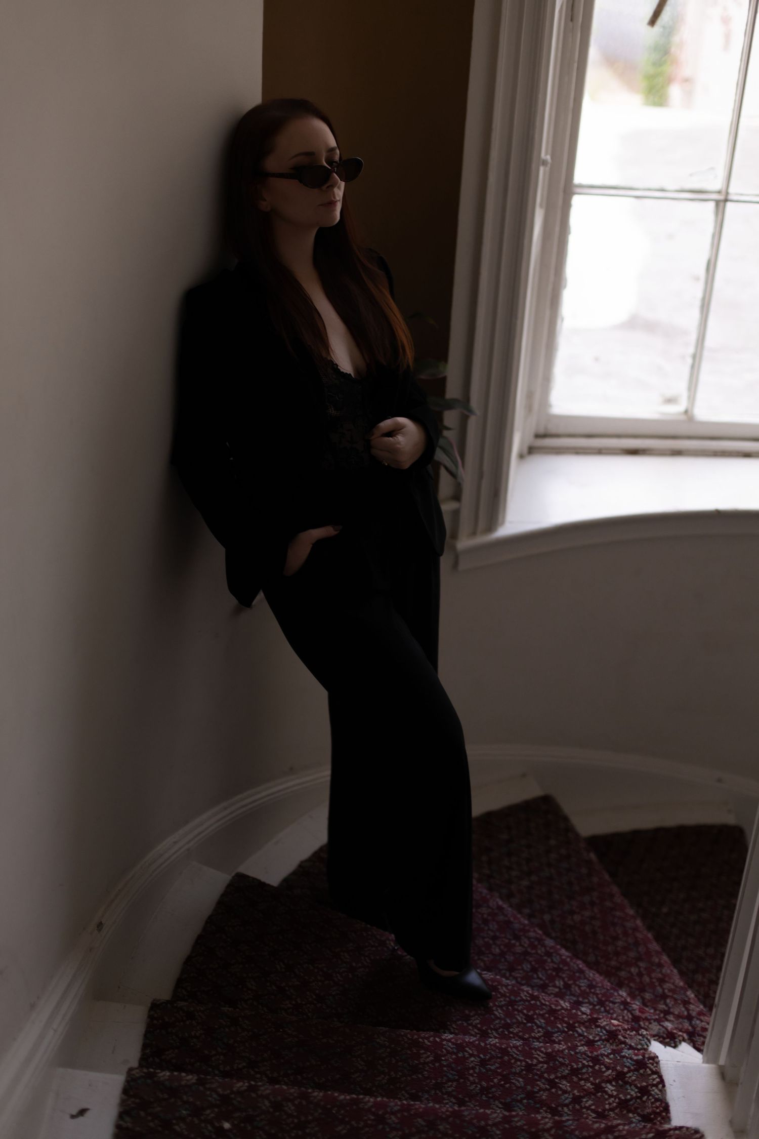 Dramatic silhouette on staircase wearing black suit and sunglasses.