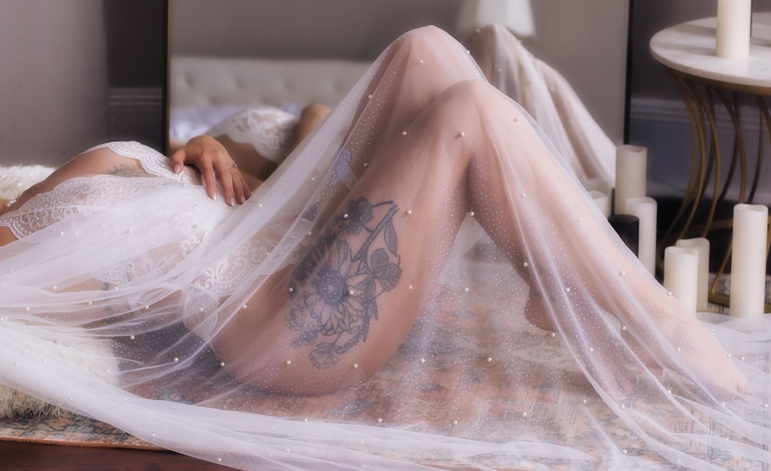 A bride in a flowing white tulle dress poses elegantly on stairs in romantic bridal portraits.