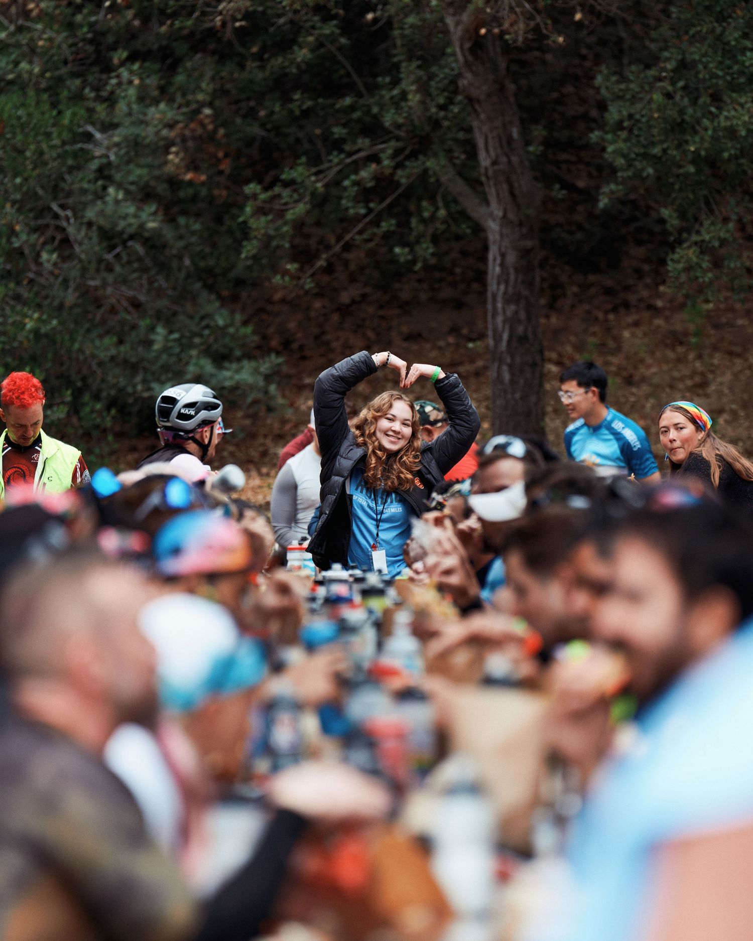 Crowd of spectators with helmets and hats gathered at outdoor sporting event.