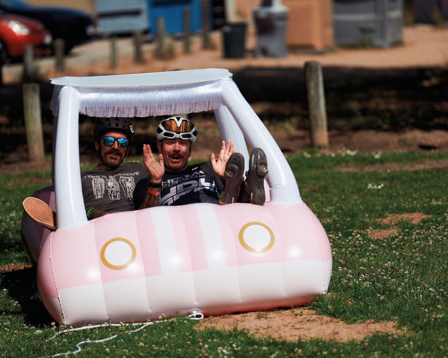 Person sitting in inflatable pink toy car prop during AIDS LifeCycle event.