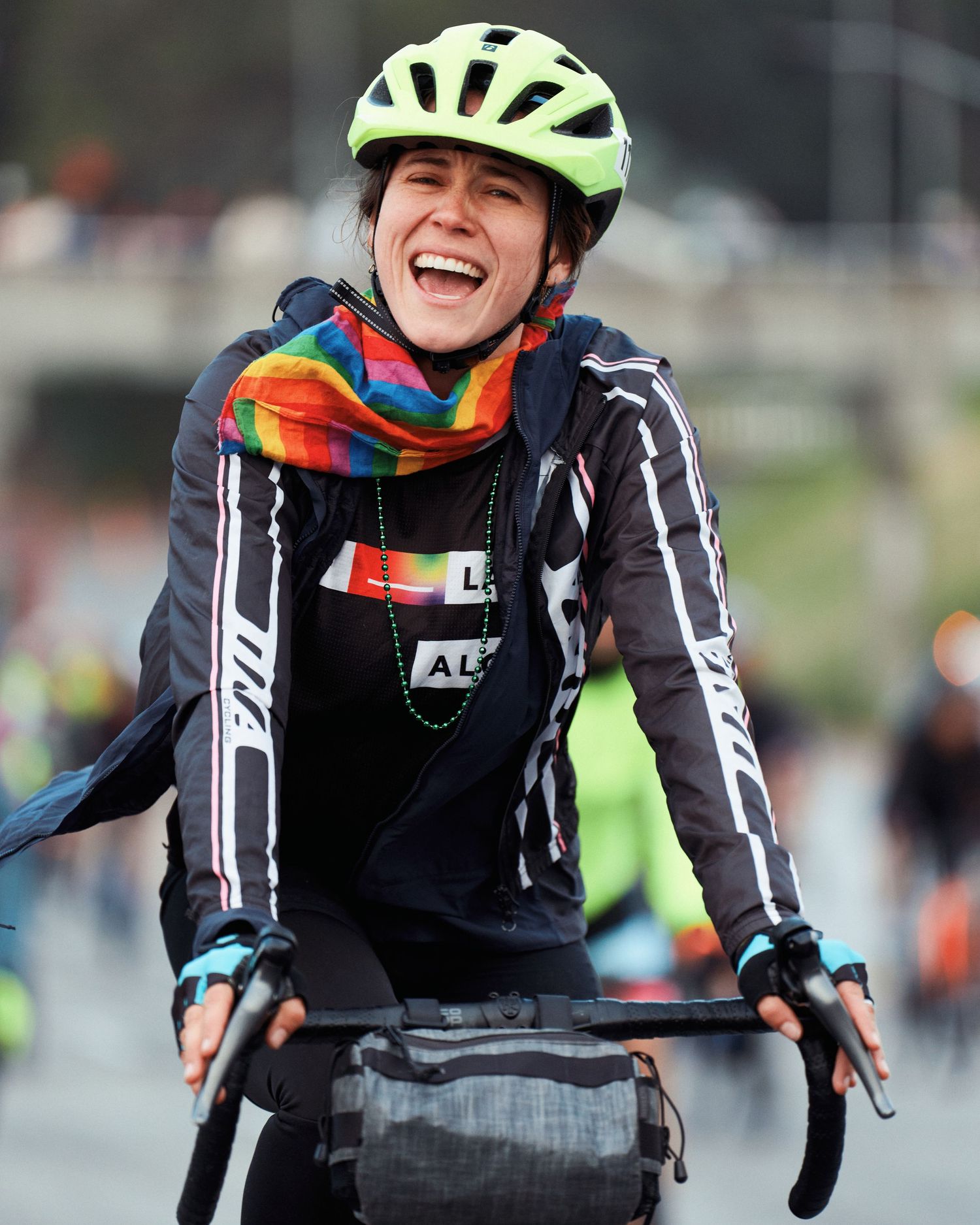 Cyclist wearing a neon safety helmet and black jacket while riding outdoors.