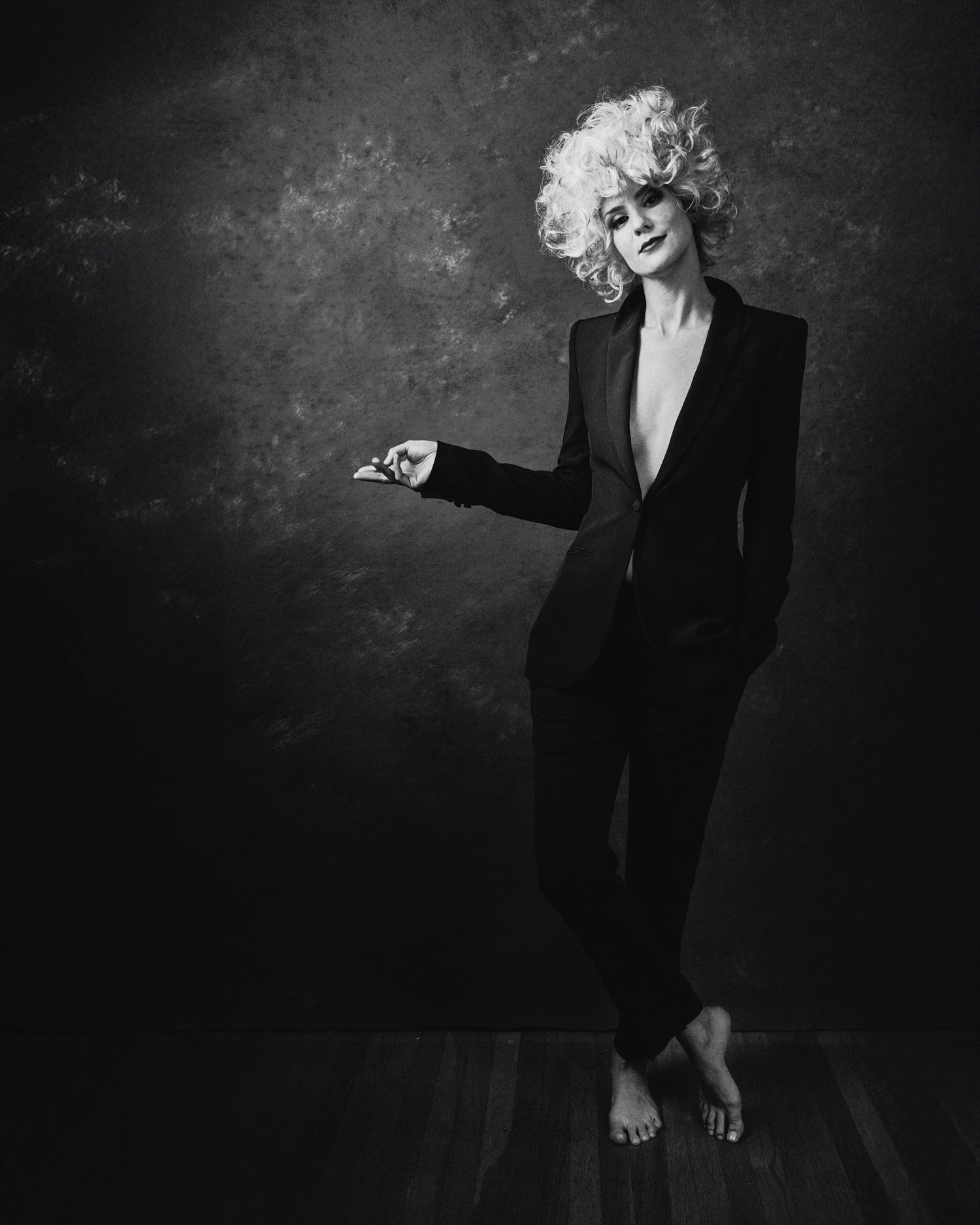 Black and white portrait series showing a person in a dark suit against a textured backdrop expressing dramatic poses.