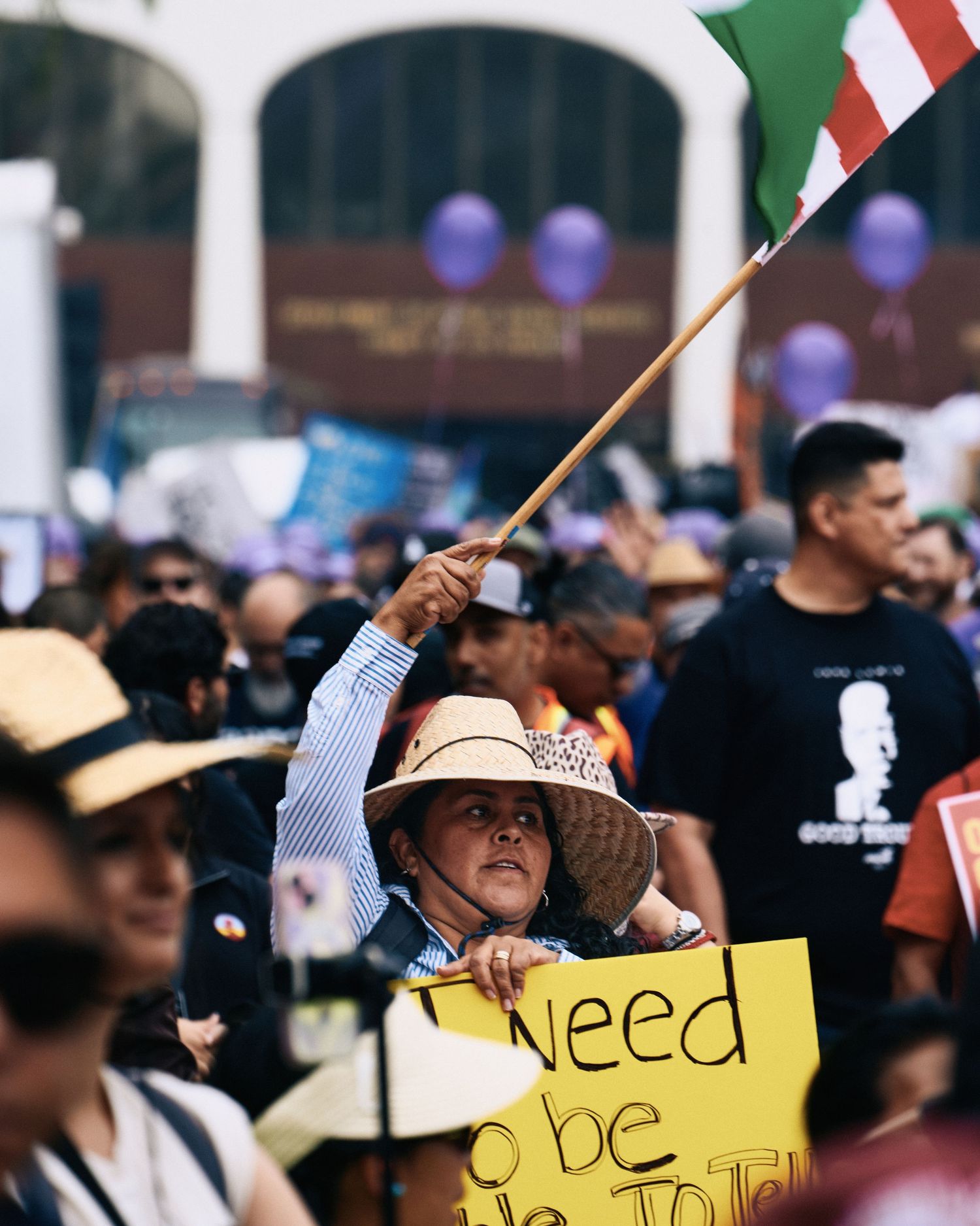 A demonstrator waves a Mexican flag and holds a protest sign during the May Day rally at MacArthur Park, Los Angeles, May 1, 2026.