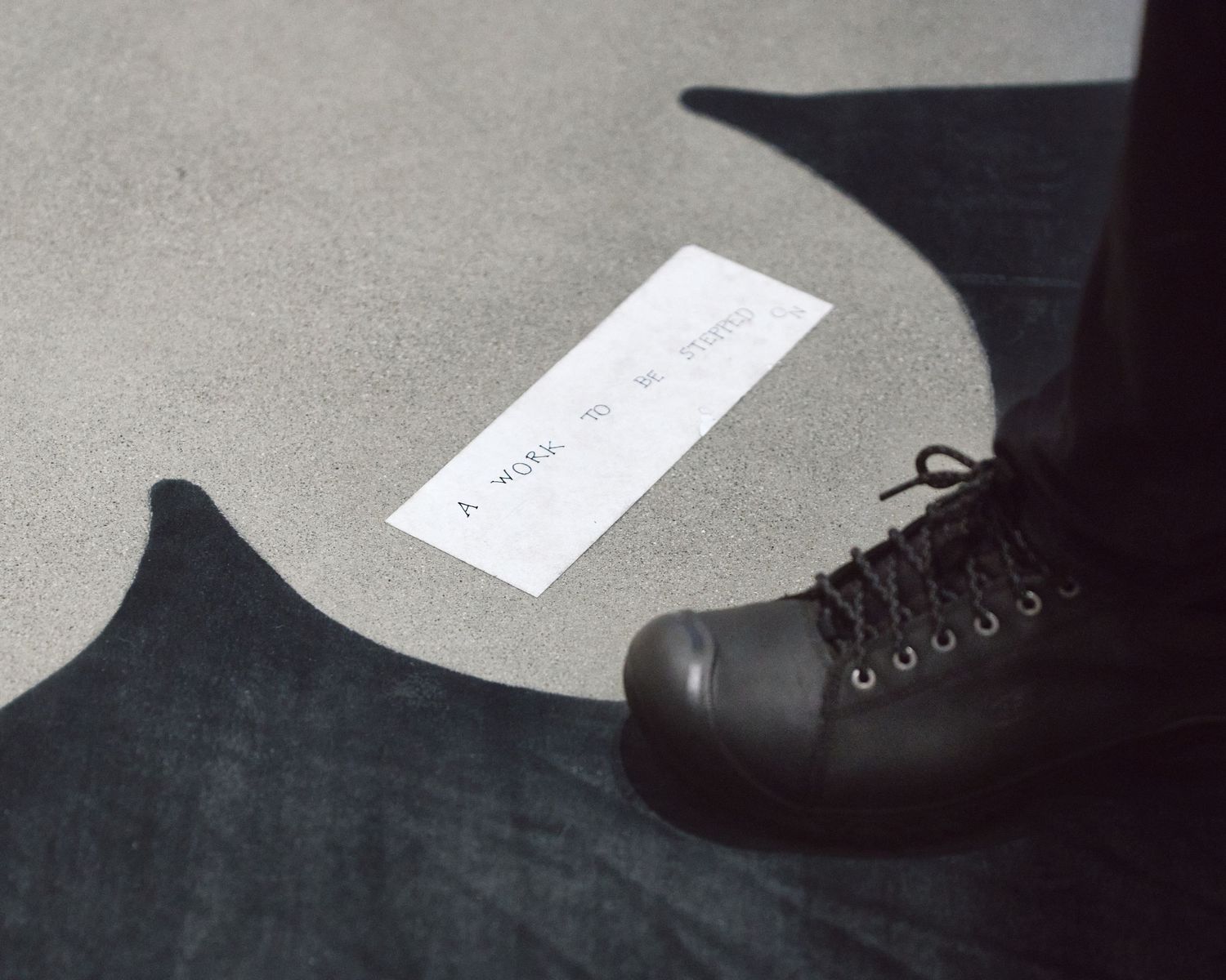 A visitor’s work boot at the edge of Yoko Ono’s Painting to Be Stepped On, a canvas laid on the gallery floor at The Broad.