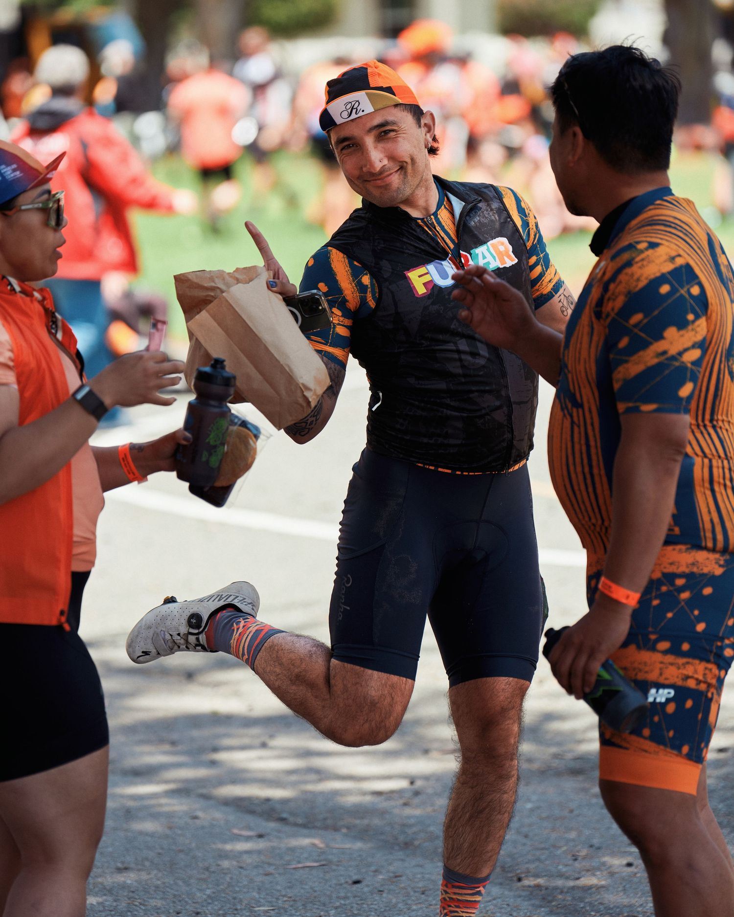 Group of athletes perform knee raises in a synchronized outdoor exercise routine wearing orange and blue gear.