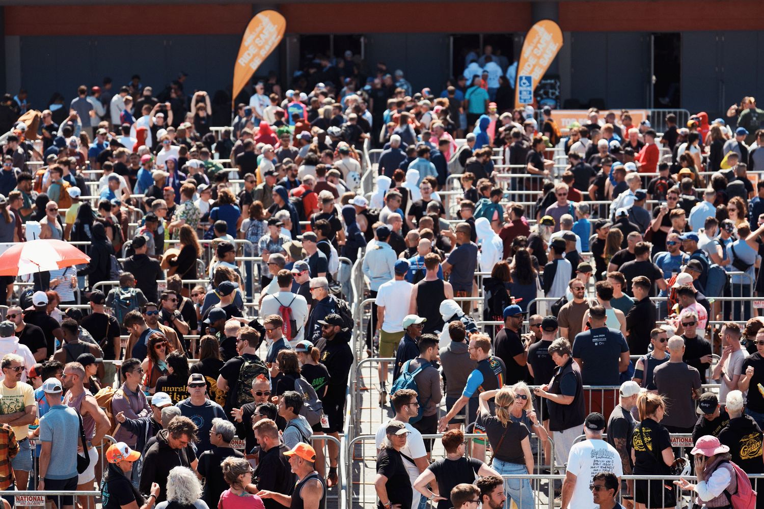 Large crowd of diverse spectators filling stands at a sports event or entertainment venue during daytime.