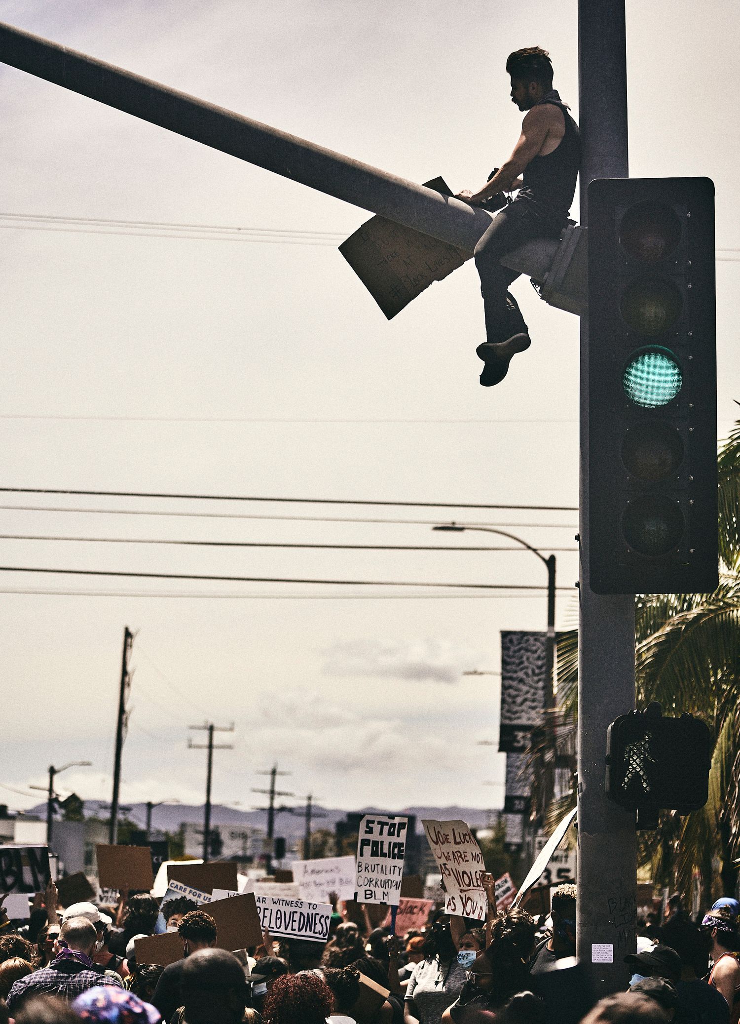 A protester sits atop a traffic signal above marchers during a BLM demonstration in Los Angeles, June 2020. (Afonso Salcedo)