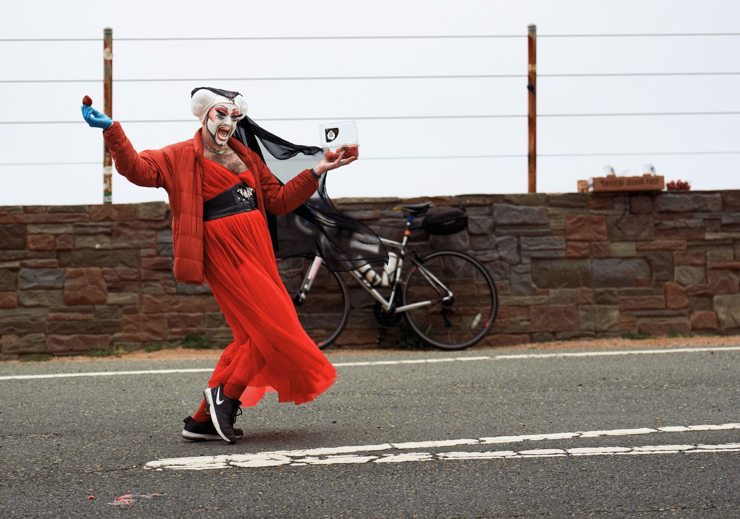 Person performing a playful jump or dance move on an urban street with red clothing.