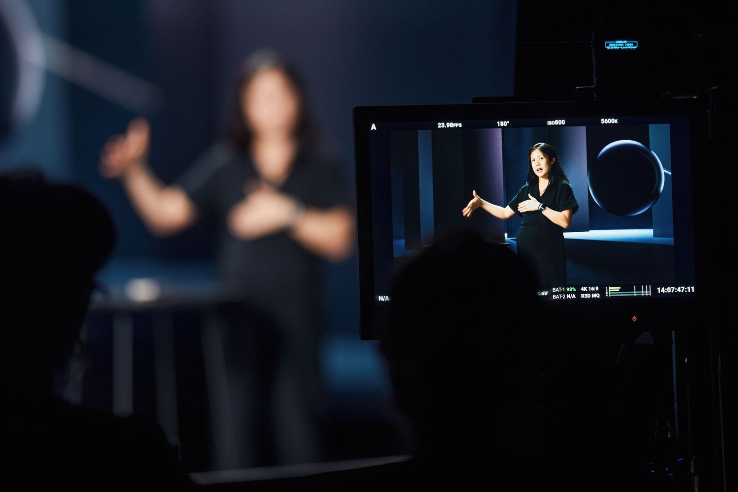 A camera viewfinder display shows a figure presenting against a dark background with dramatic lighting.