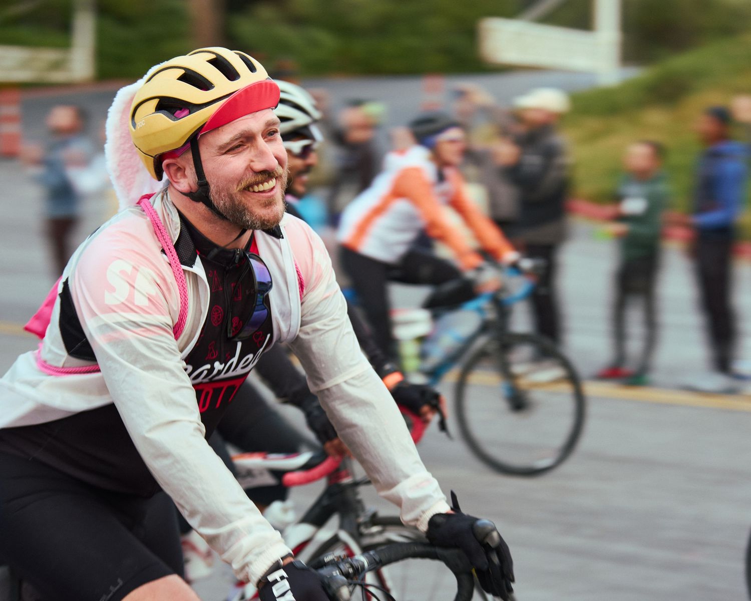 Cyclist wearing reflective gear rides in rainy conditions during an event.