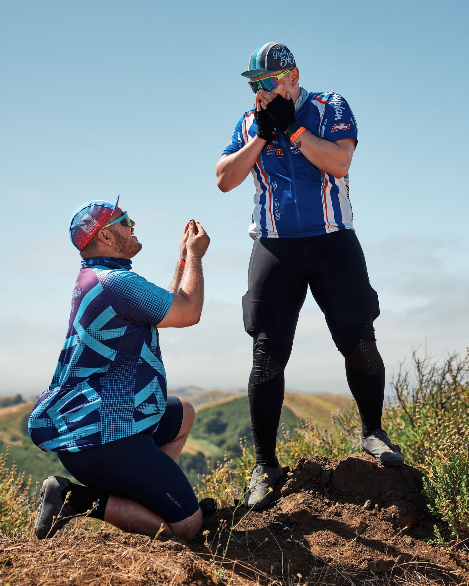 Two cyclists share a candid moment on a hilltop as one photographs the other.