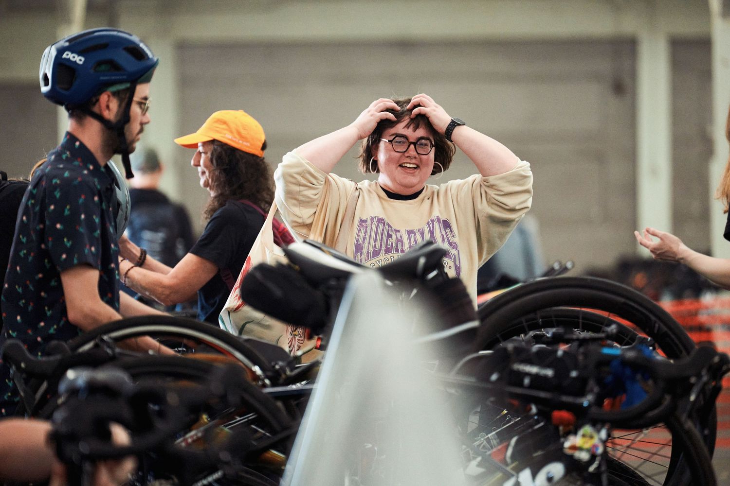 A group of people gather around motorcycles as one expresses excitement at a bike meetup event.