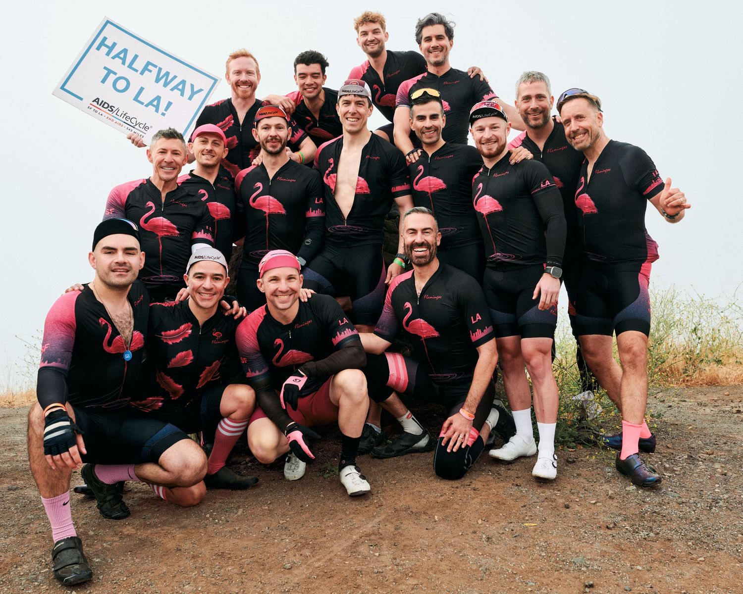 A team photo of rugby players wearing black uniforms with red accents posing together outdoors.