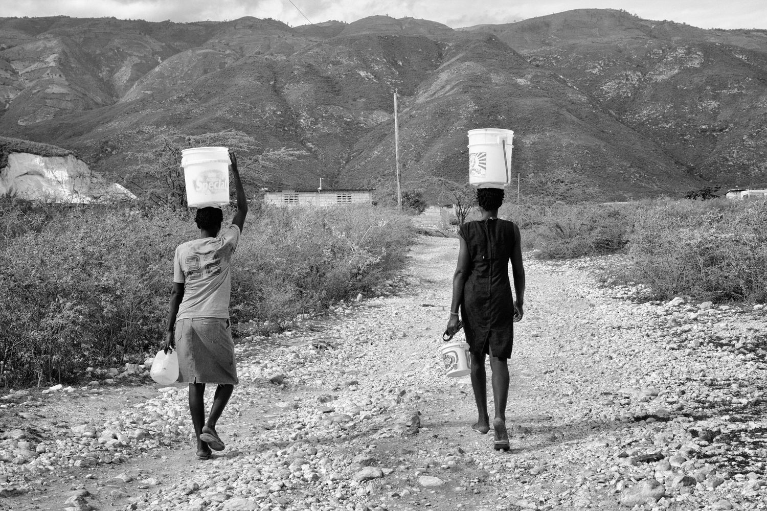 Two women carry water along a dirt path outside Fond Parisien, Haiti, Sept. 2013. (Afonso Salcedo)