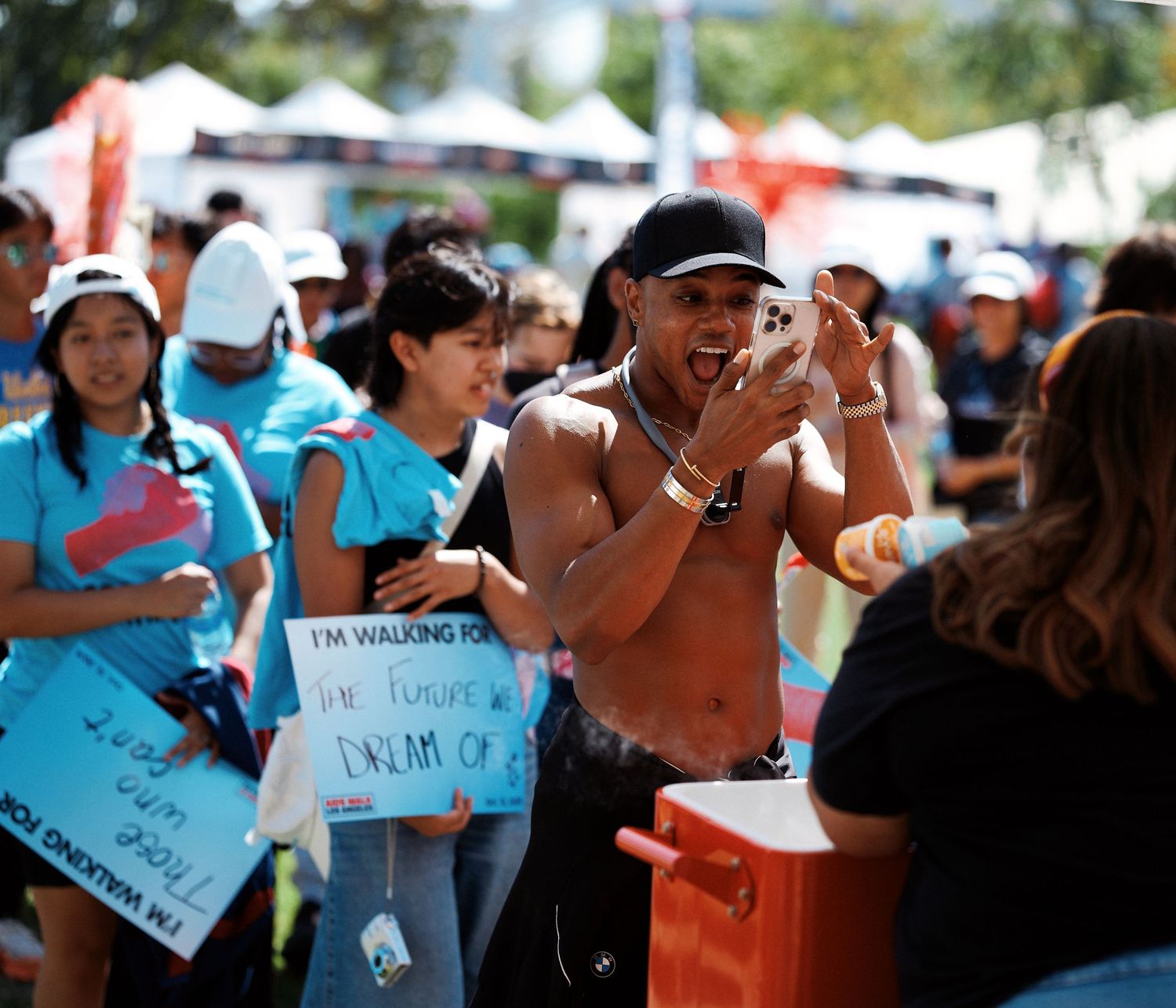 A group of people holding signs and cheering during an outdoor protest or rally on a sunny day.