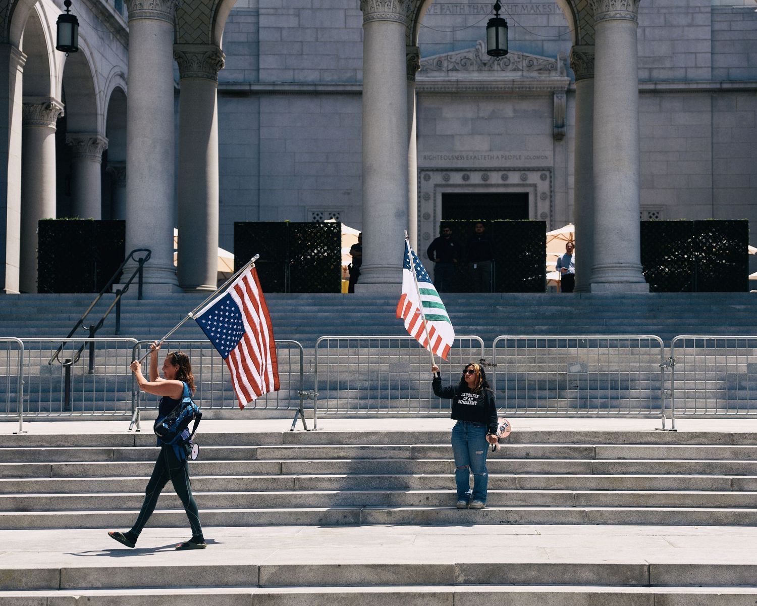 Two demonstrators carry American flags on the steps of Los Angeles City Hall during the May Day rally, May 1, 2026.