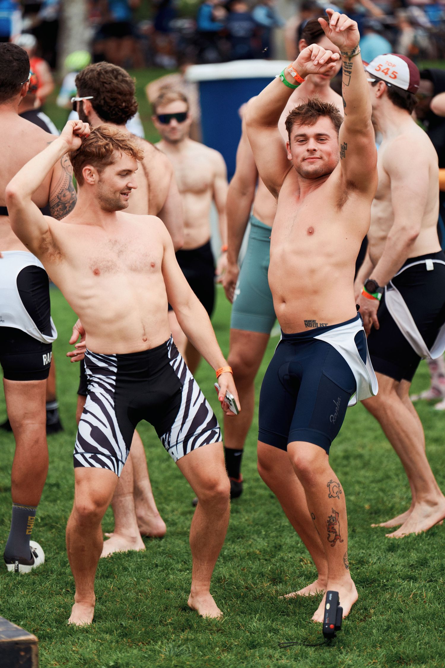 Shirtless male rugby players performing a traditional haka dance ritual on grass field while wearing zebra-striped shorts.