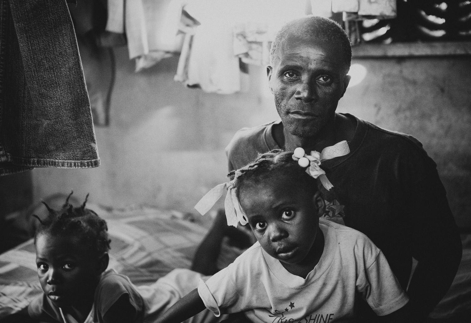 A man and his two children inside their home in Fond Parisien, Haiti, Sept. 2013. (Afonso Salcedo)