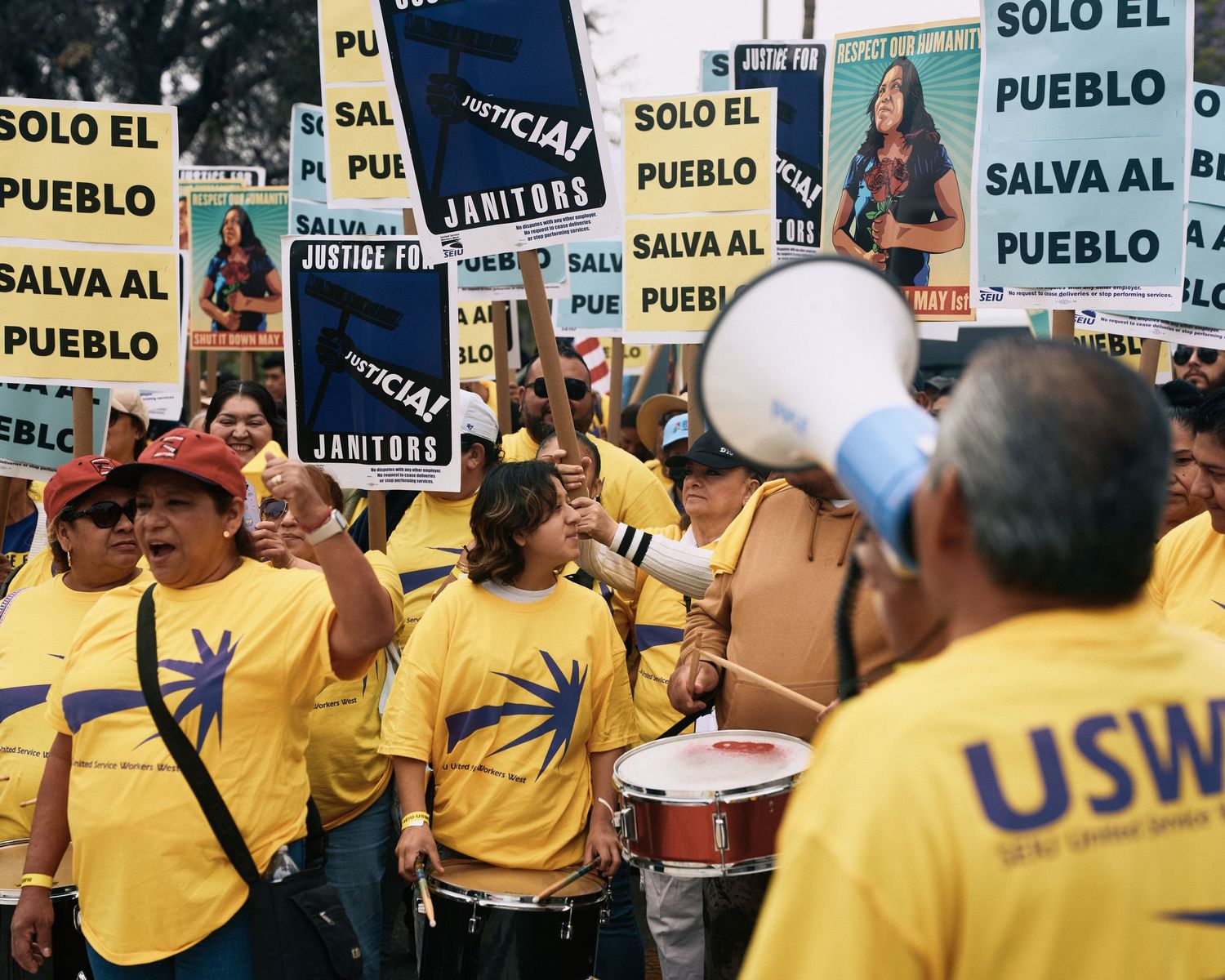 SEIU United Service Workers West members march with drums and Justice for Janitors signs at May Day rally, MacArthur Park, Los Angeles, 2026