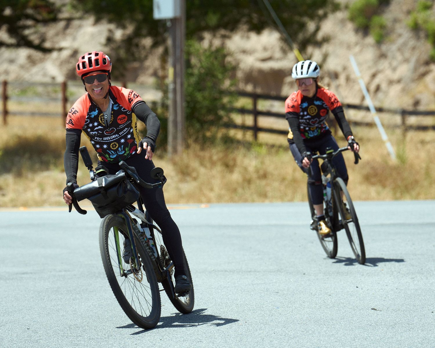 Two cyclists in red jerseys riding bikes along a winding mountain road.