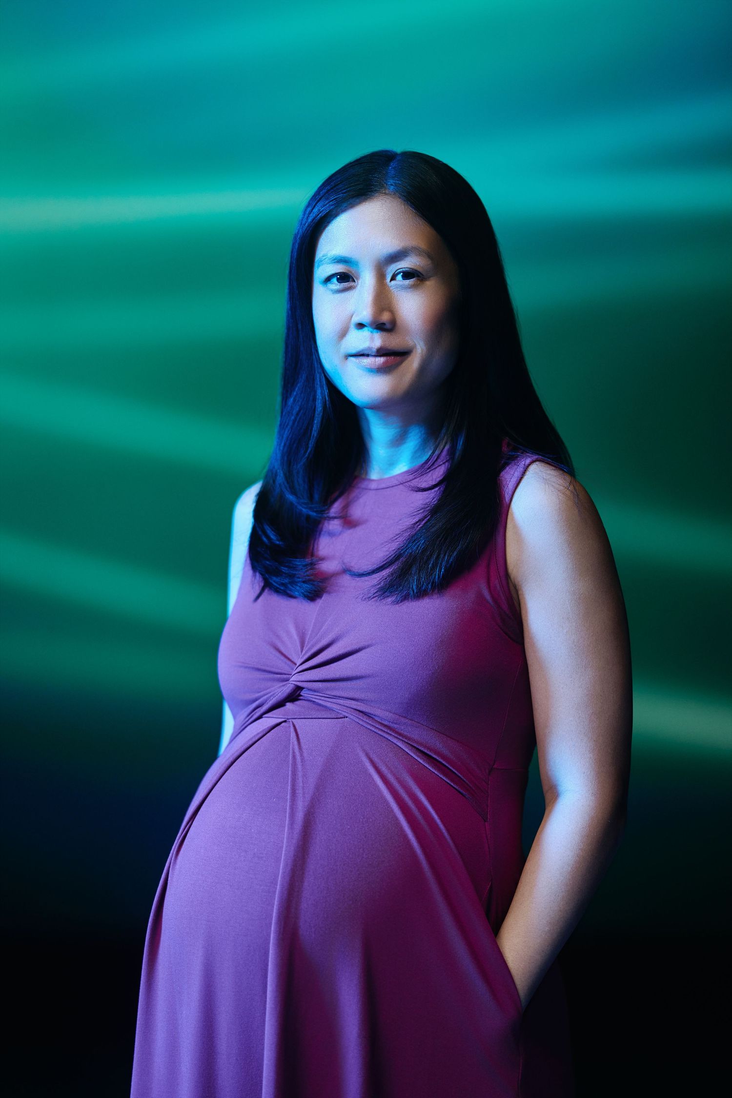 A person in a purple sleeveless top poses against a teal background with dramatic lighting effects.