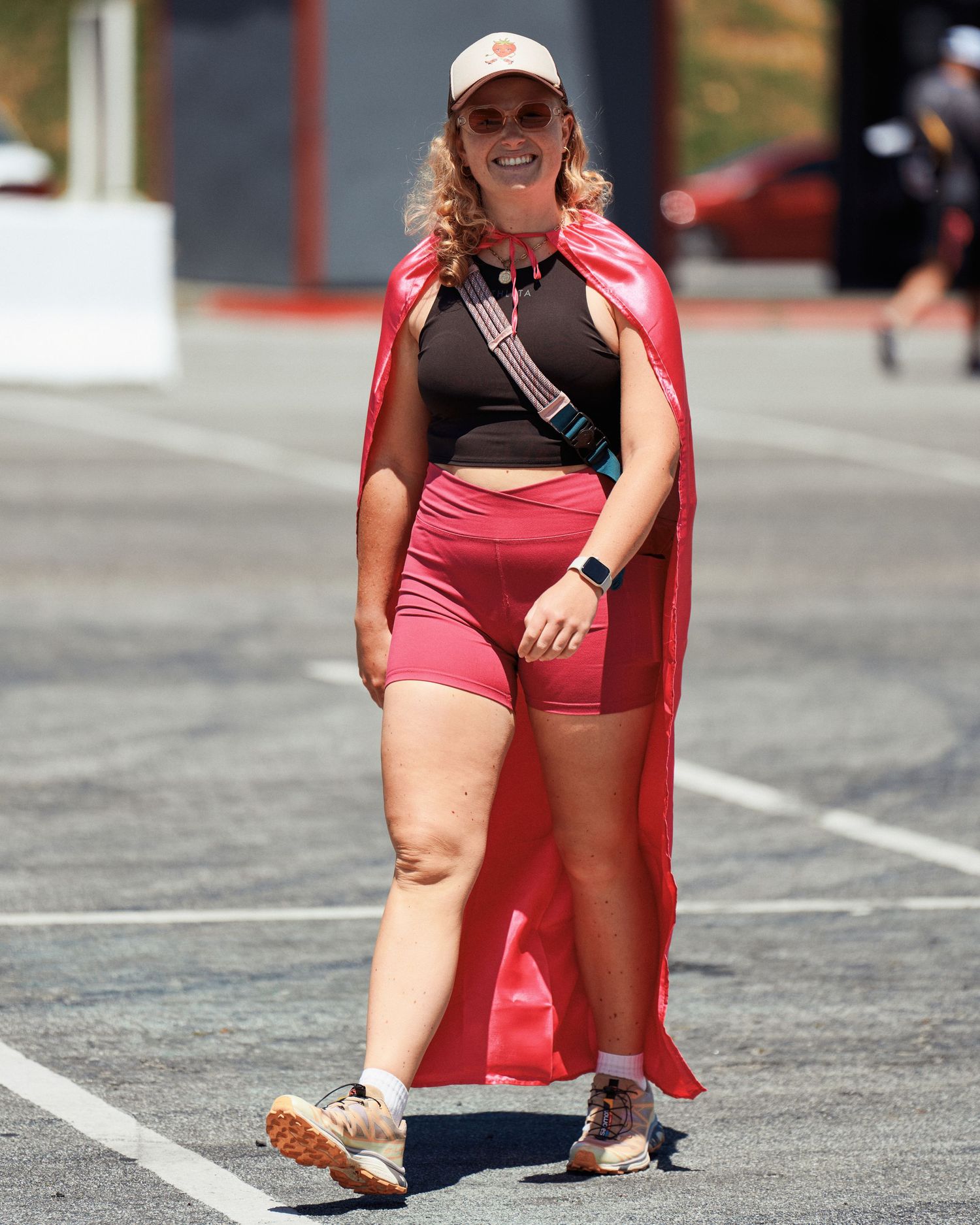 Someone in red sportswear holding a phone while stretching outdoors on a sunny day.