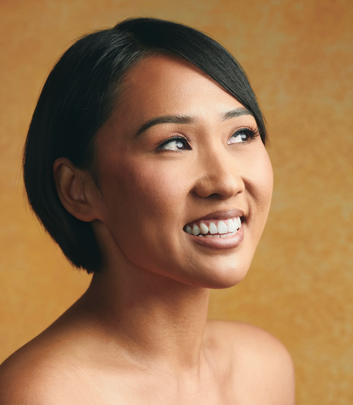 A series of headshots showing joyful expressions and genuine smiles against a warm brown background.