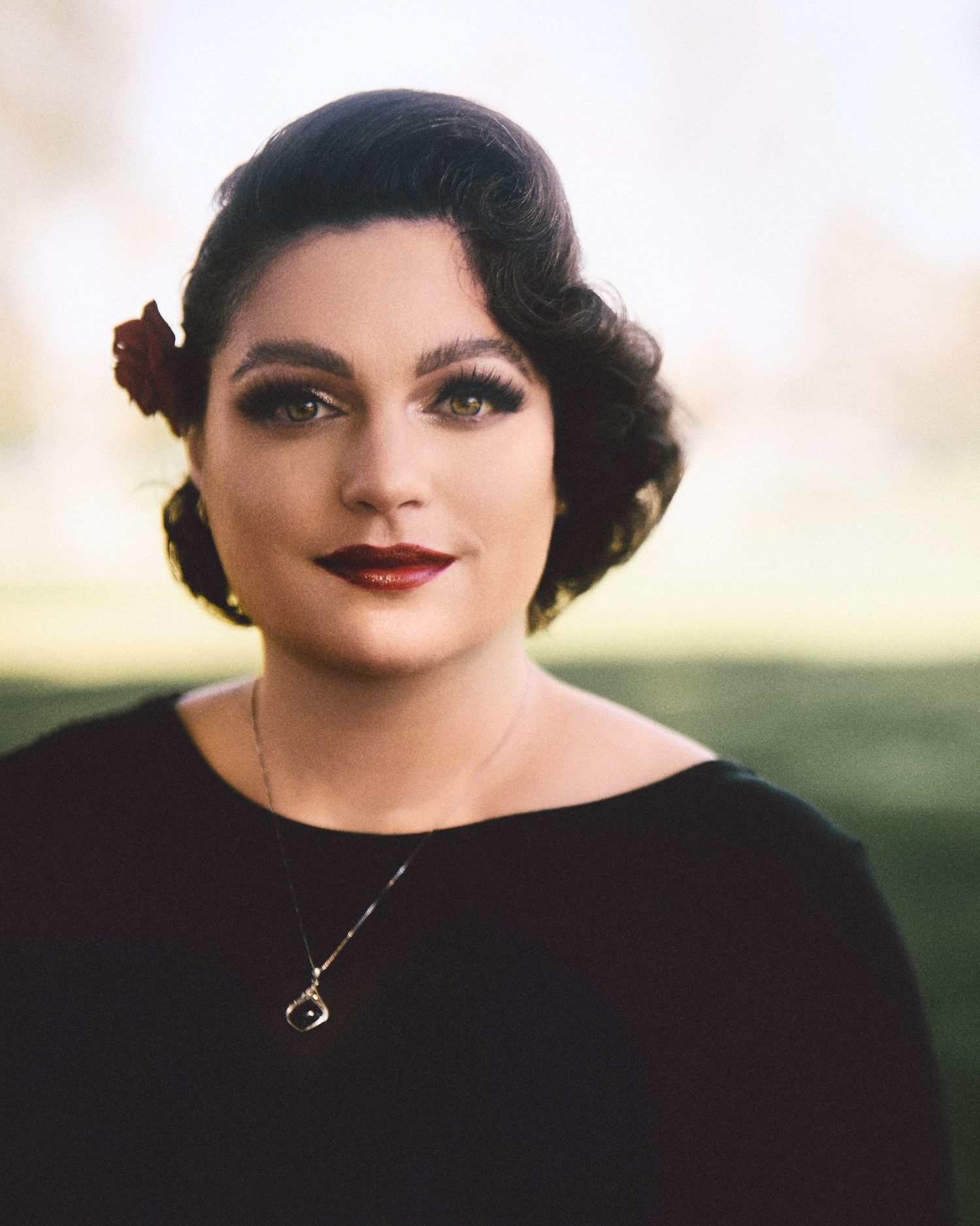 A person wearing a black top with dark hair and red lipstick is seen in five repeated closeup portraits.