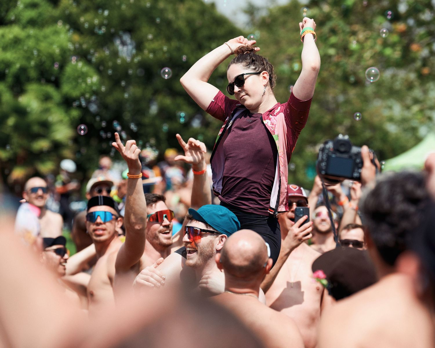 Festival goer being lifted above crowd with arms raised during outdoor summer concert event.