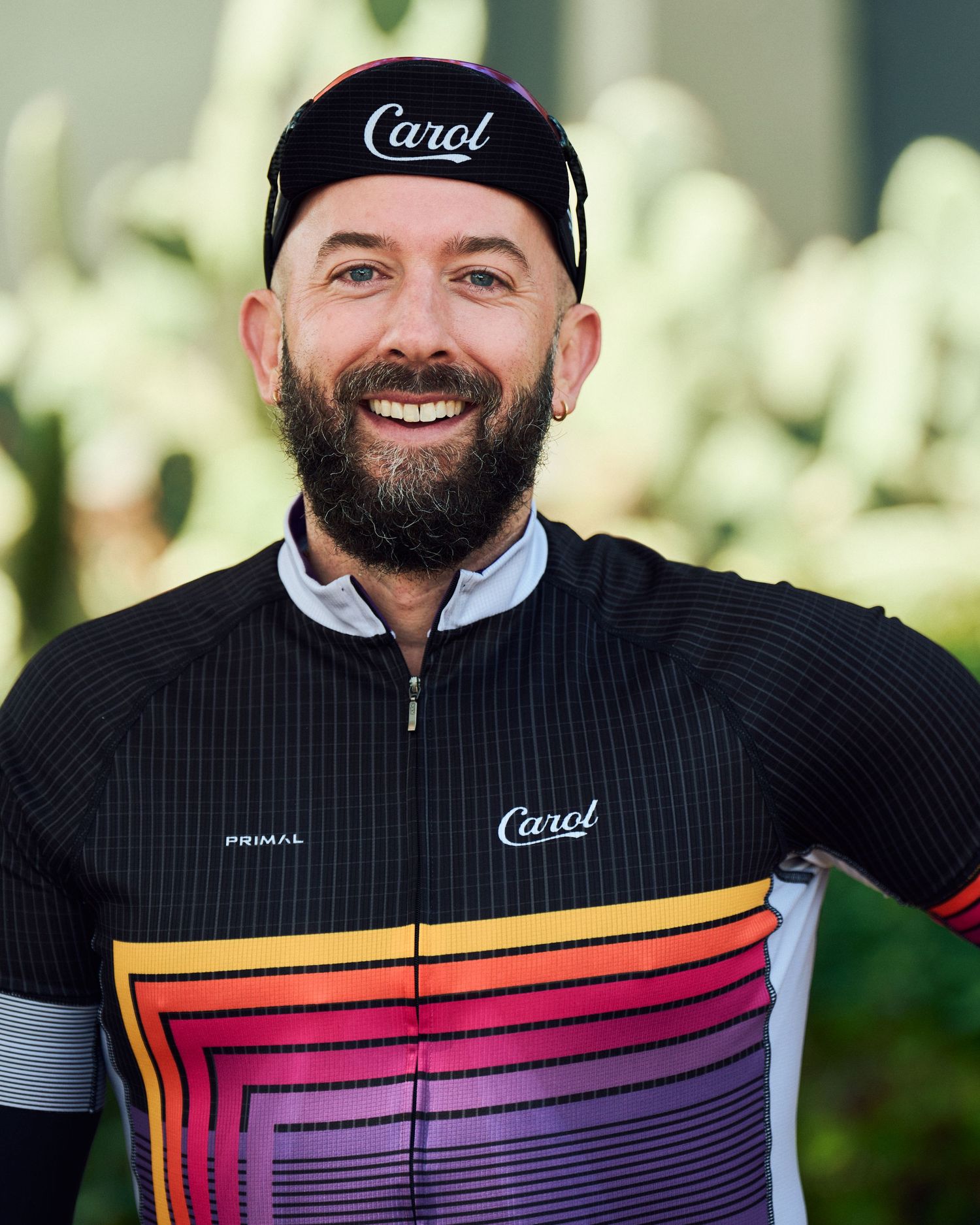 Cyclist in black cap wearing striped jersey with gradient sunset colors from orange to purple.