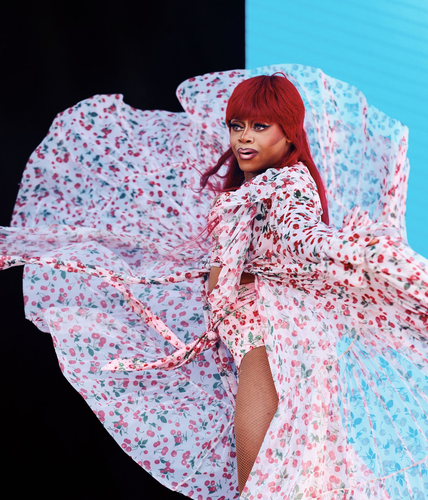 A flowing white dress with red floral print twirls against a bright blue background in a dynamic fashion sequence.
