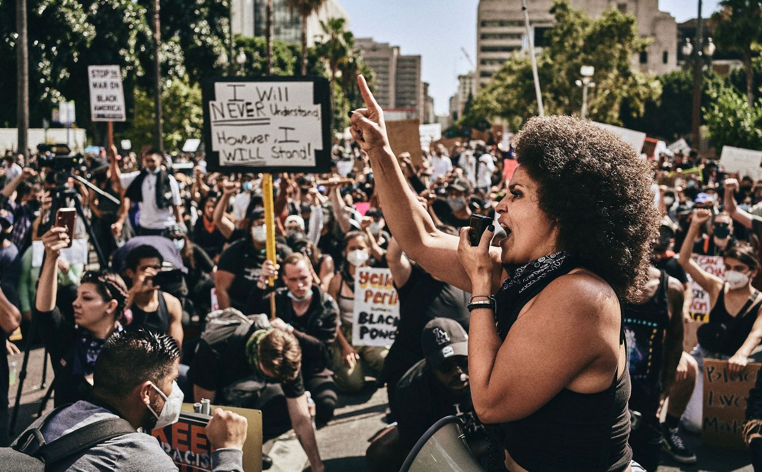 A speaker addresses a kneeling crowd during a Black Lives Matter demonstration in Los Angeles, June 2020. (Afonso Salcedo)