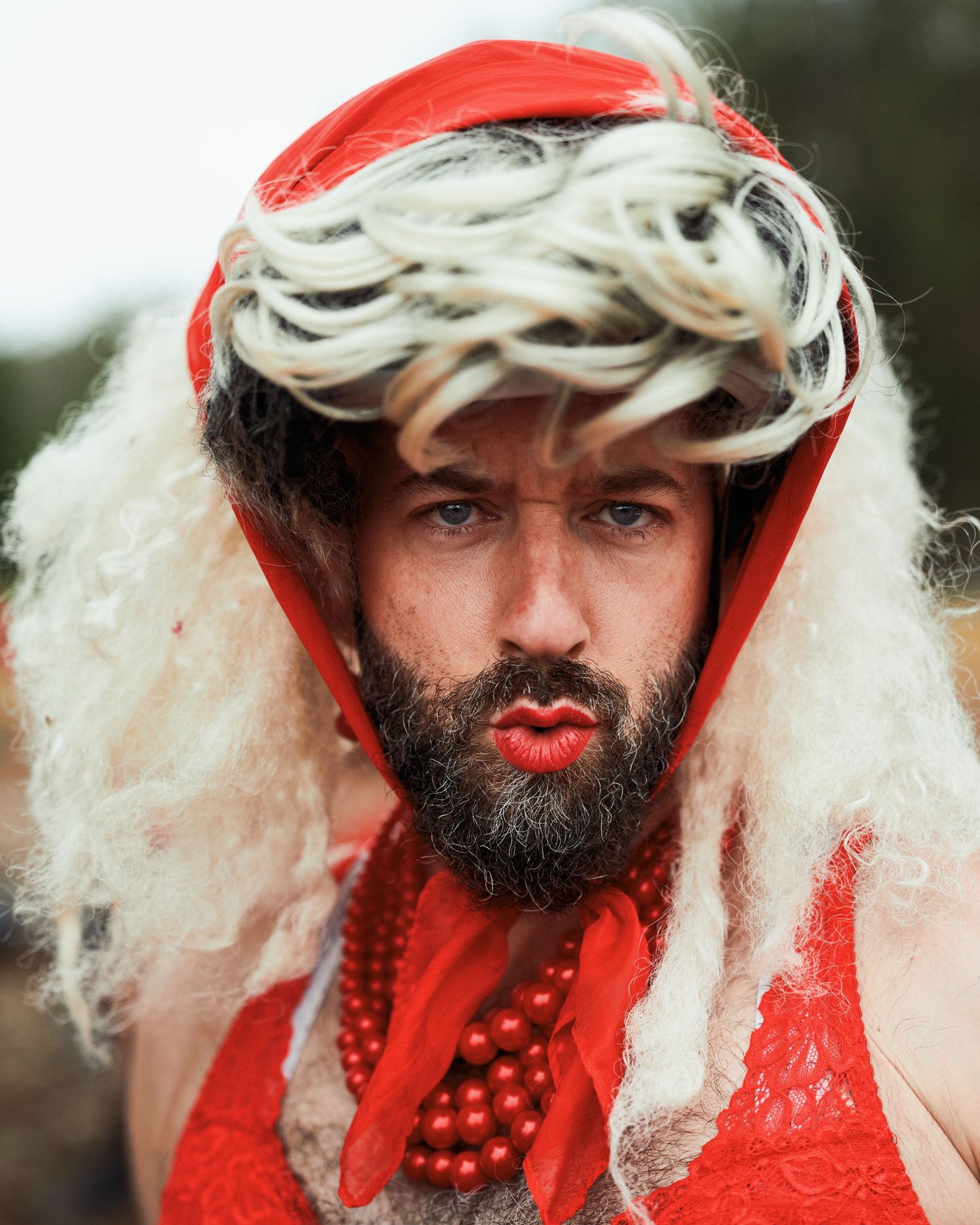 A cyclist wearing a red hood and white wig as part of a festive holiday costume looks at the camera.