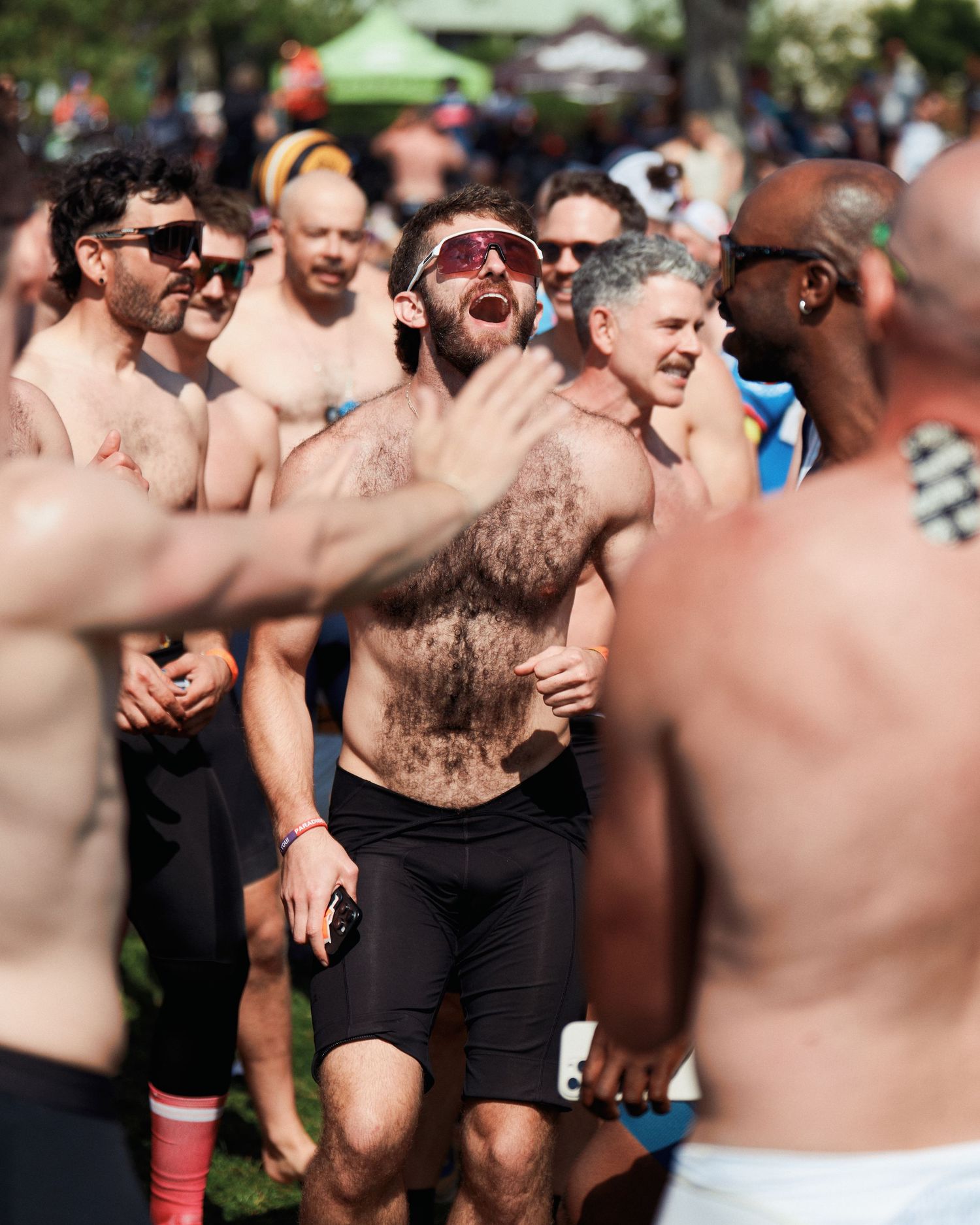 Shirtless crowd of energetic participants celebrating and cheering at outdoor festival or event.