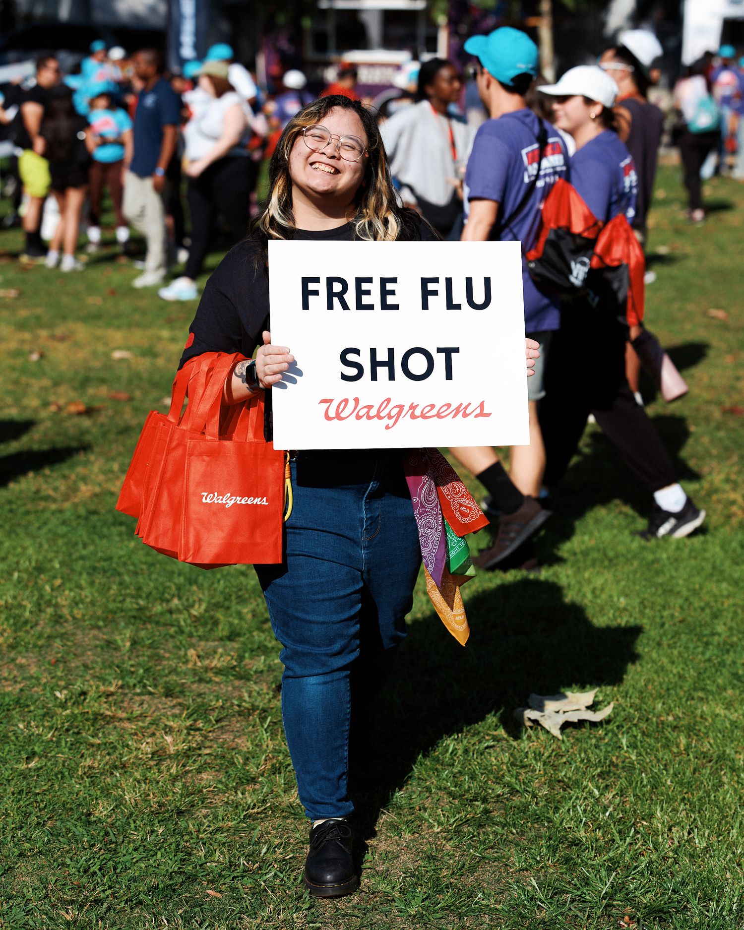People walking on grass holding signs advertising free flu shots at a community health event.
