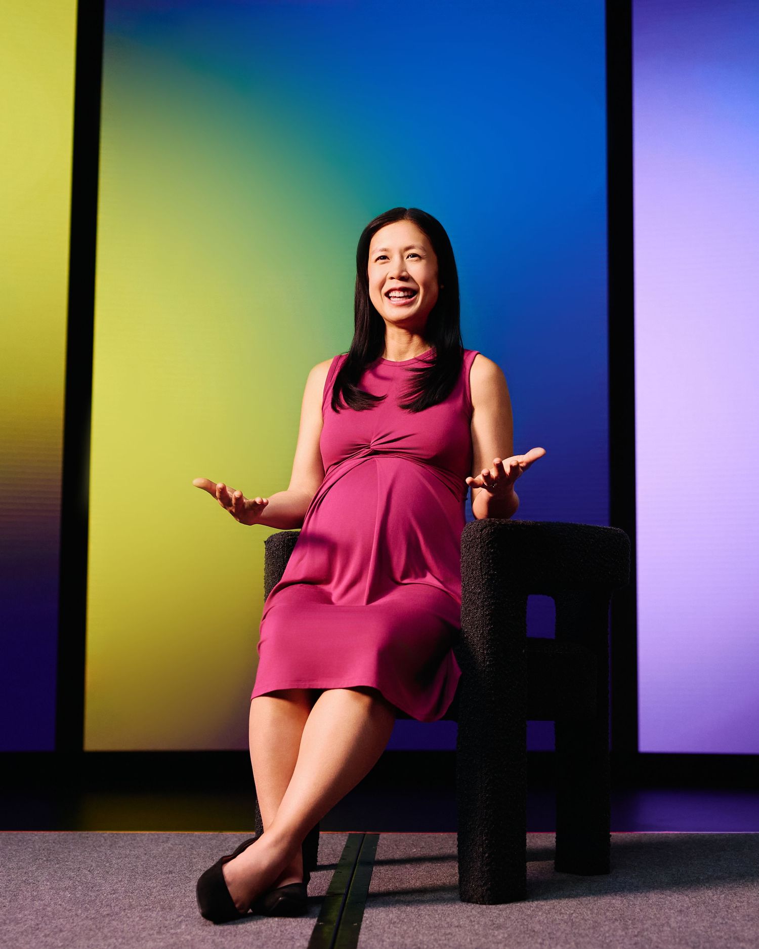 Seated portrait of the Udemy course presenter in a magenta dress against colorful LED panels, photographed by Afonso Salcedo.