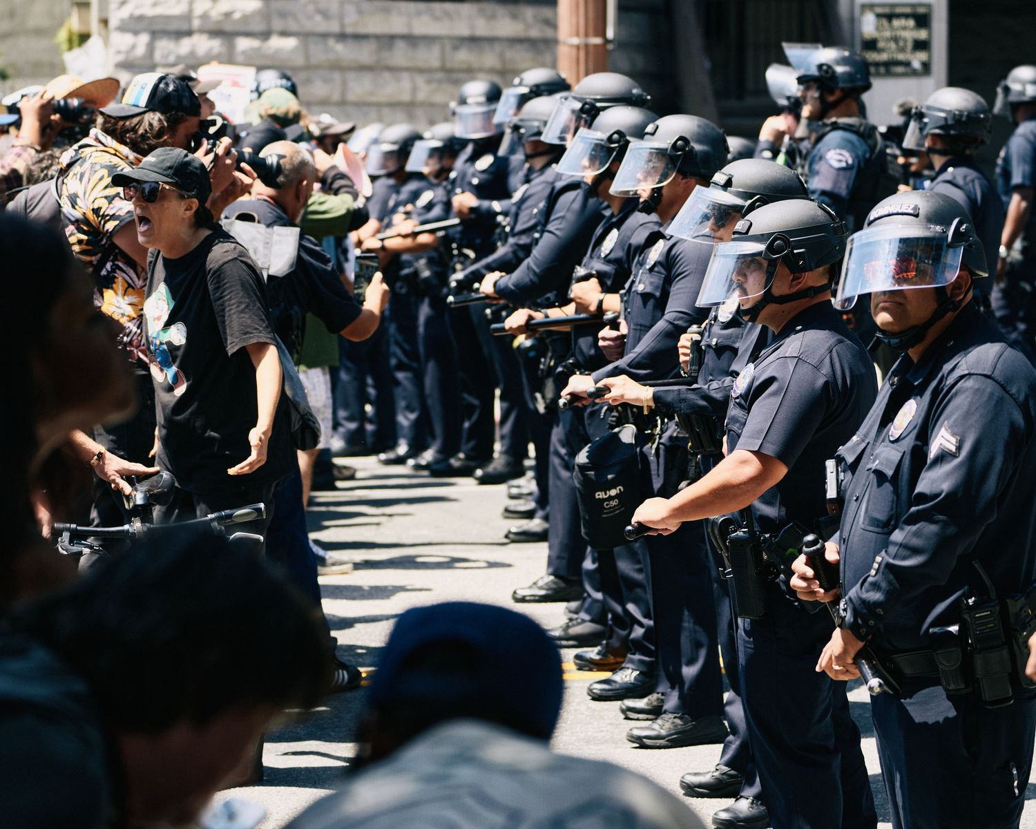 A demonstrator confronts LAPD officers in riot gear after an unlawful assembly was declared at the May Day rally, Los Angeles, May 1, 2026.