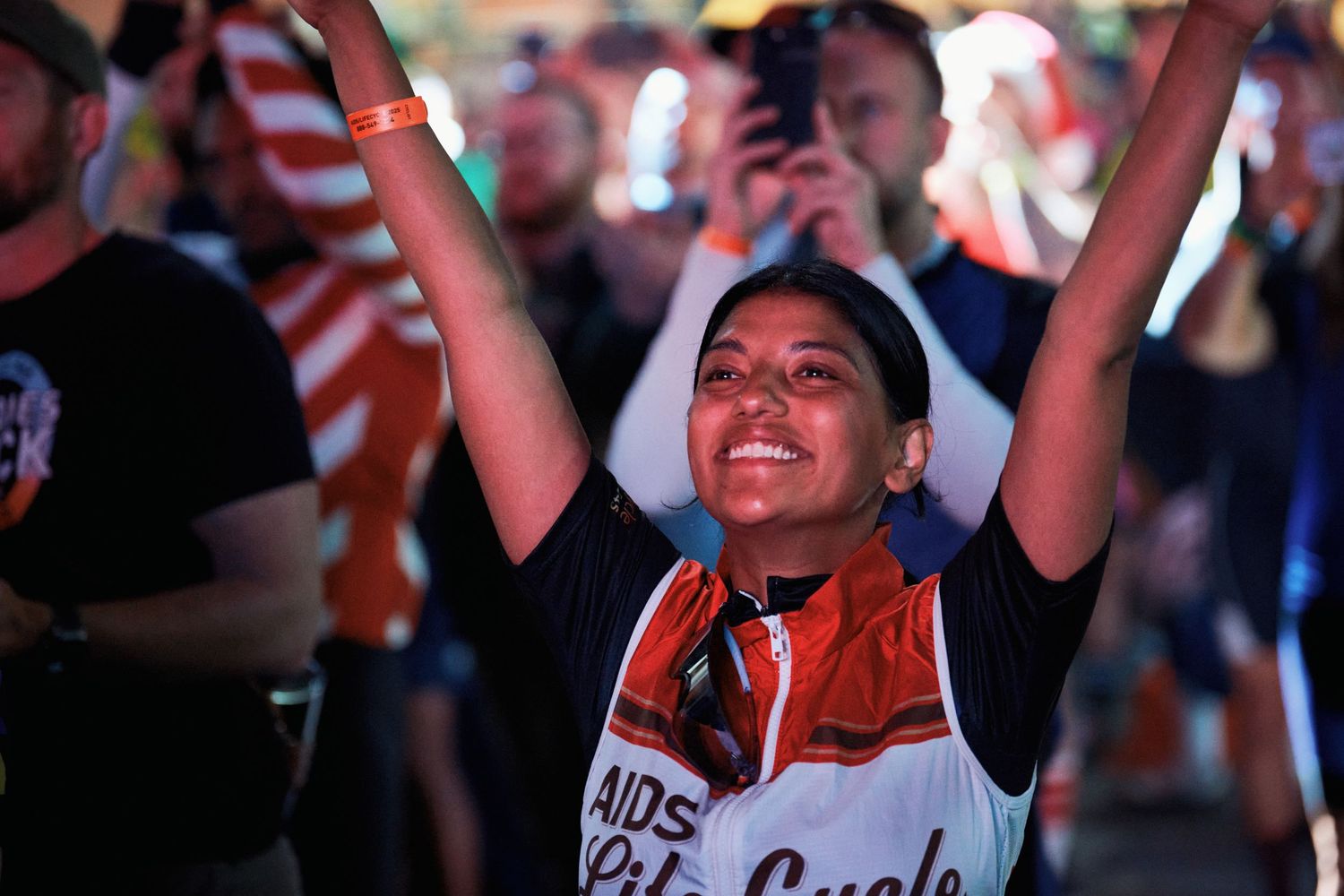 Crowd of sports fans cheering excitedly with raised arms at a live event venue.