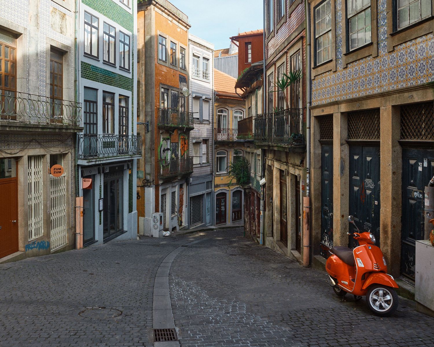 Narrow cobblestone street with historic buildings and colorful facades in Porto, Portugal.